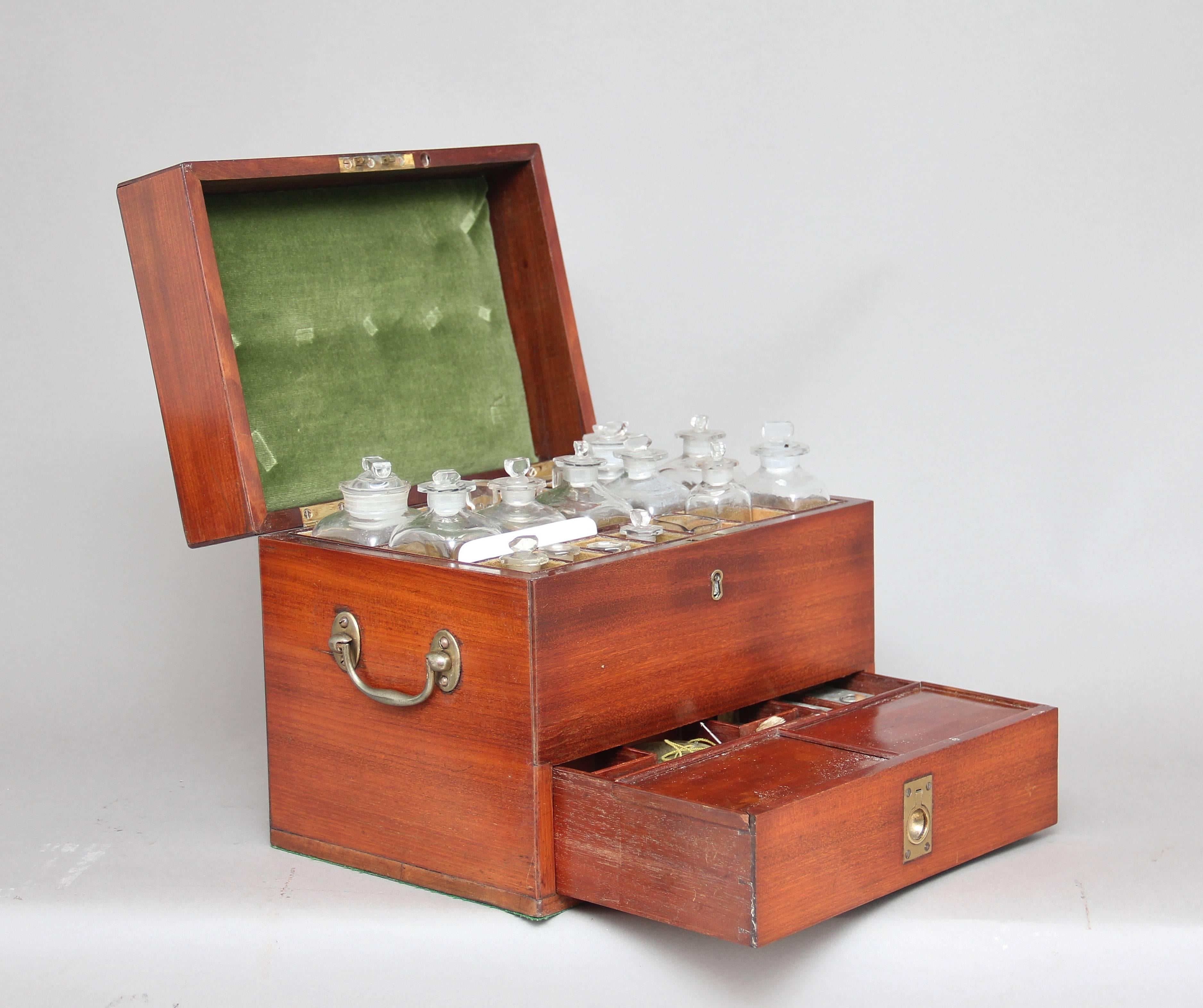 19th century mahogany apothecary box of good proportions, with original brass swan neck carrying handles at the sides, the hinged top opening to reveal various compartments with glass jars of various sizes, the front of the box there is a pull-out
