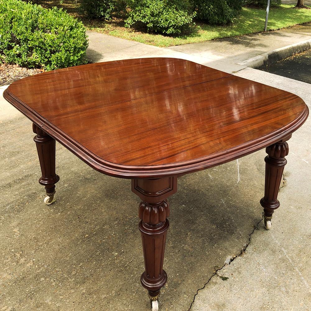 19th century mahogany banquet table with 5 leaves features bold carved, fluted and tapered legs with a single leg for the center to support the weight when fully configured. The sheer natural beauty of the exotic imported mahogany shines forth with