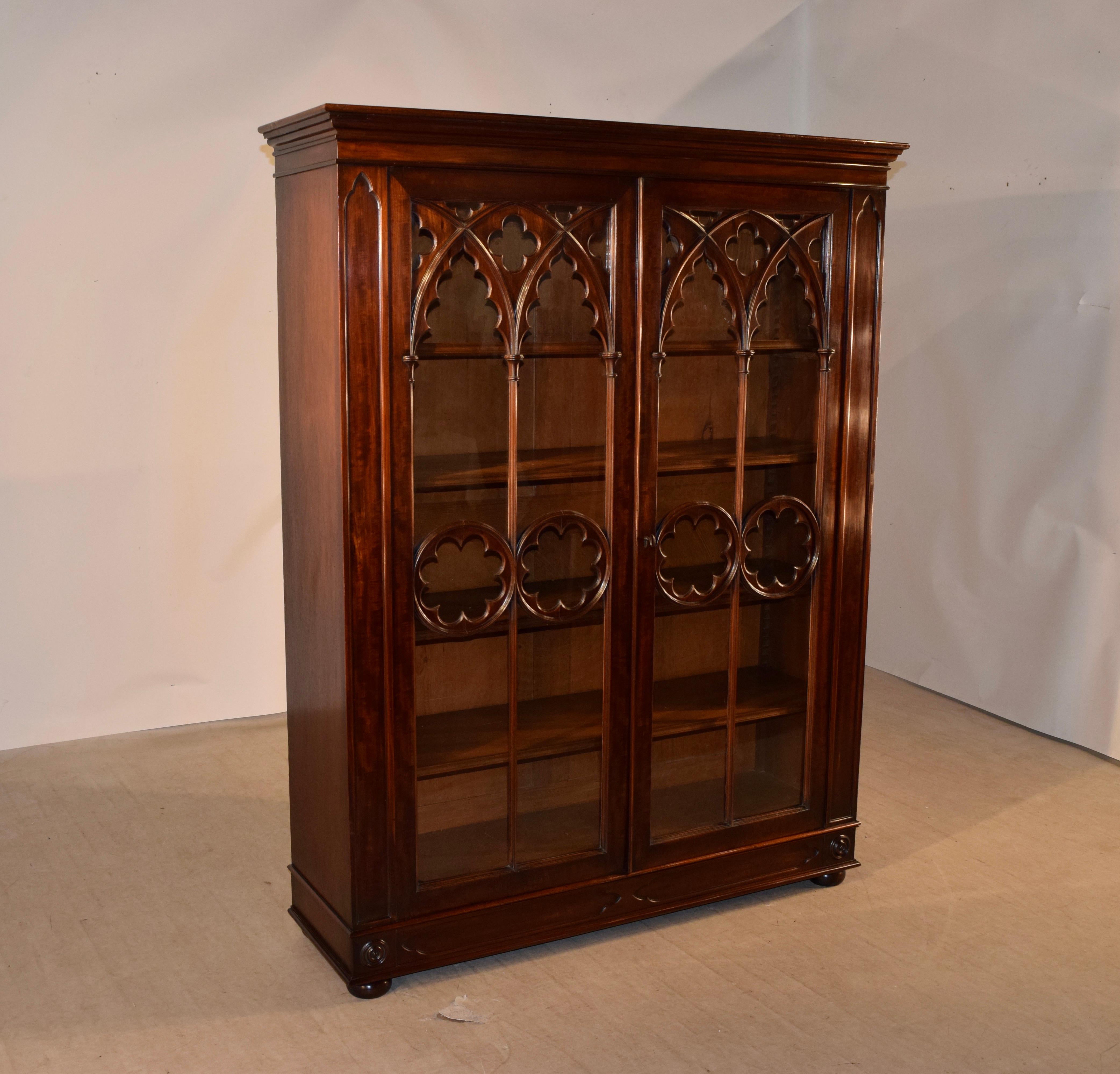 19th century mahogany bookcase from England of the Gothic period. The case has an upper crown over a simple case with wonderfully glazed doors that have hand routed and scalloped Gothic moldings. The doors open to reveal five shelves, four of which