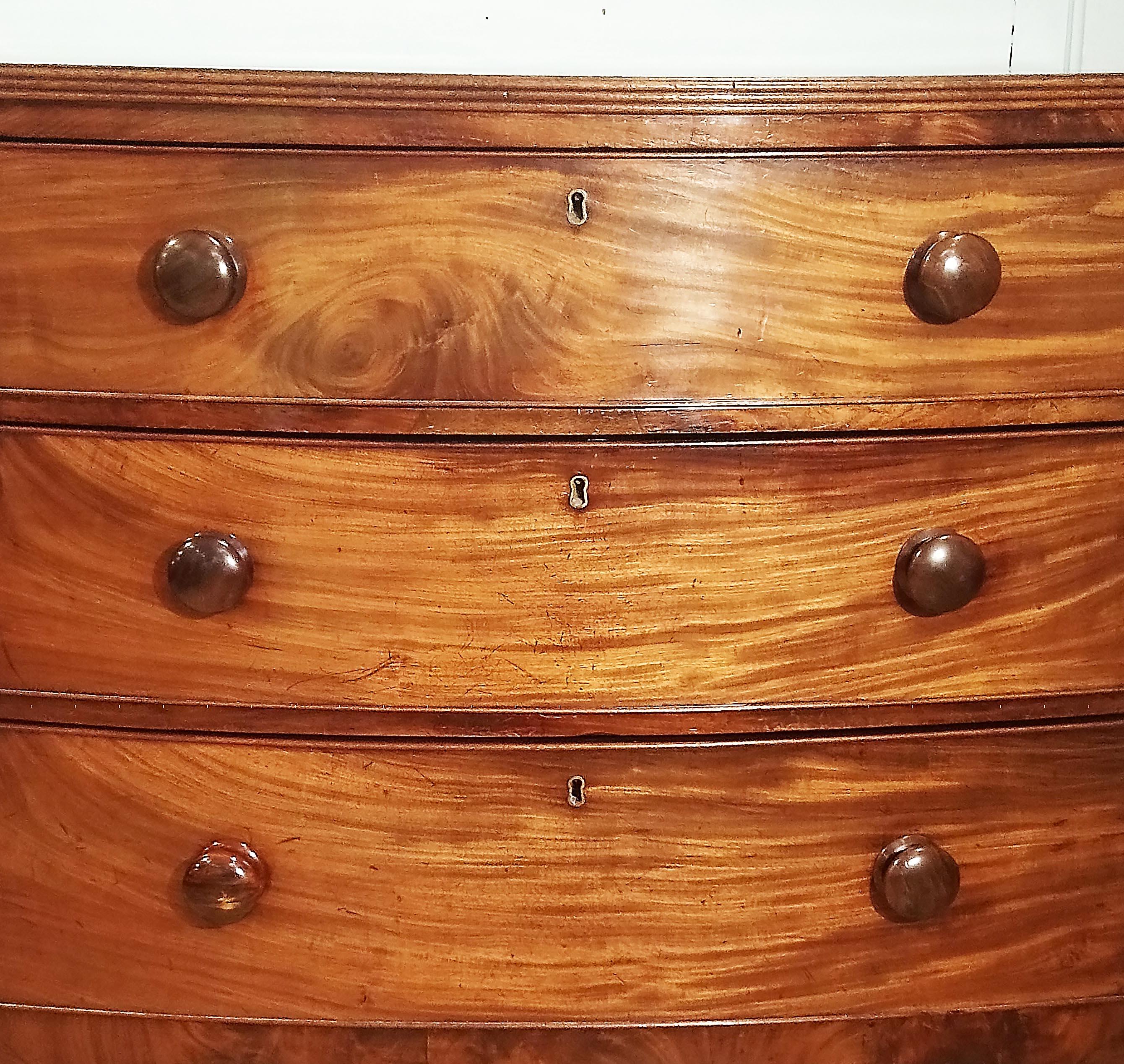 This very attractive English bow fronted chest of drawers features three long graduating drawers with turned wooden knob handles. The chest is an excellent quality piece with an understated elegance and simple design. It measures 35 in – 89 cm wide,