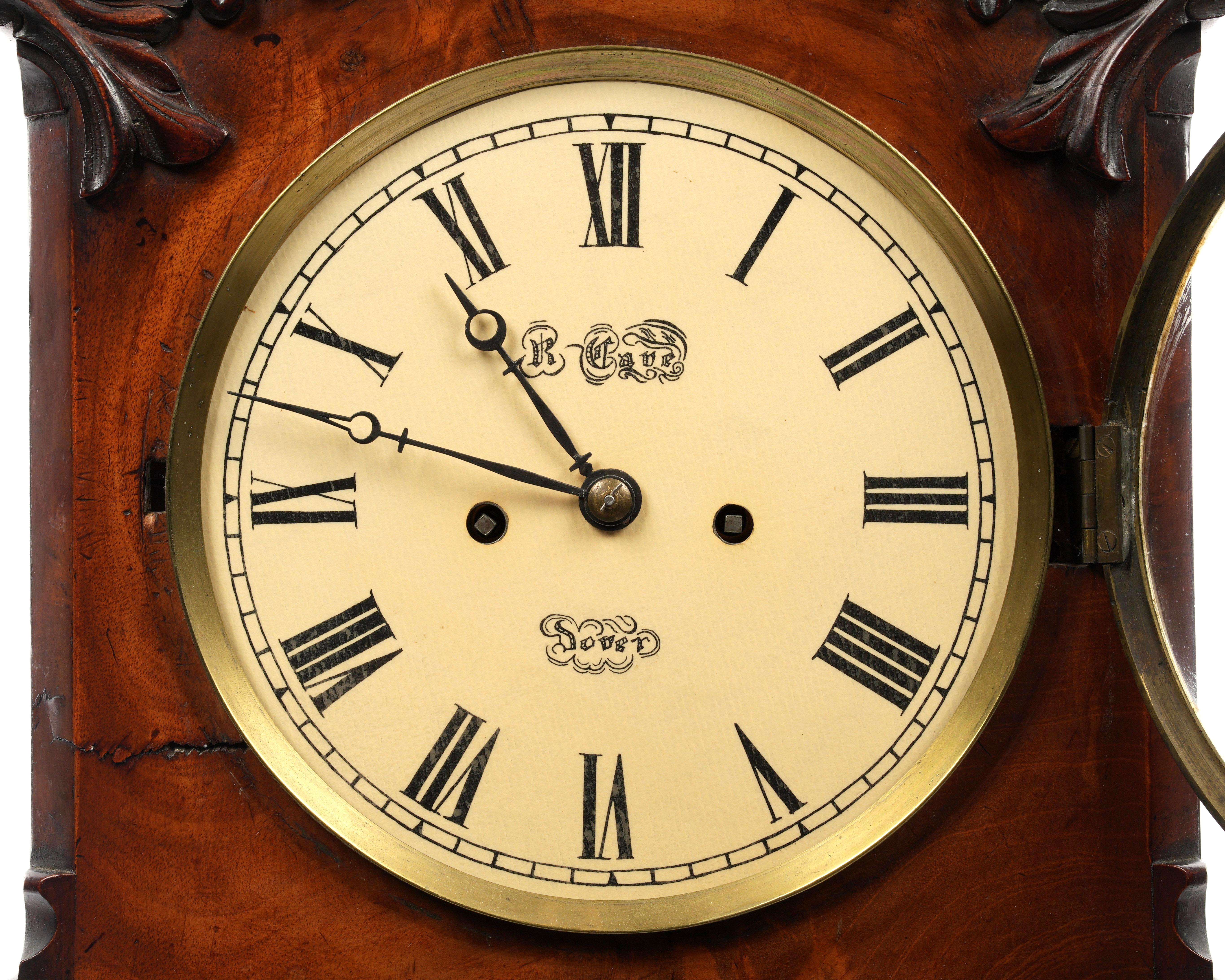 Orologio a staffa inglese a doppia spoletta del XIX secolo. L'orologio presenta una cassa in mogano intagliata a volute foliate e gadroon su quattro piedini. La cassa presenta una ricca venatura e una decorazione a volute d'acanto intagliate che