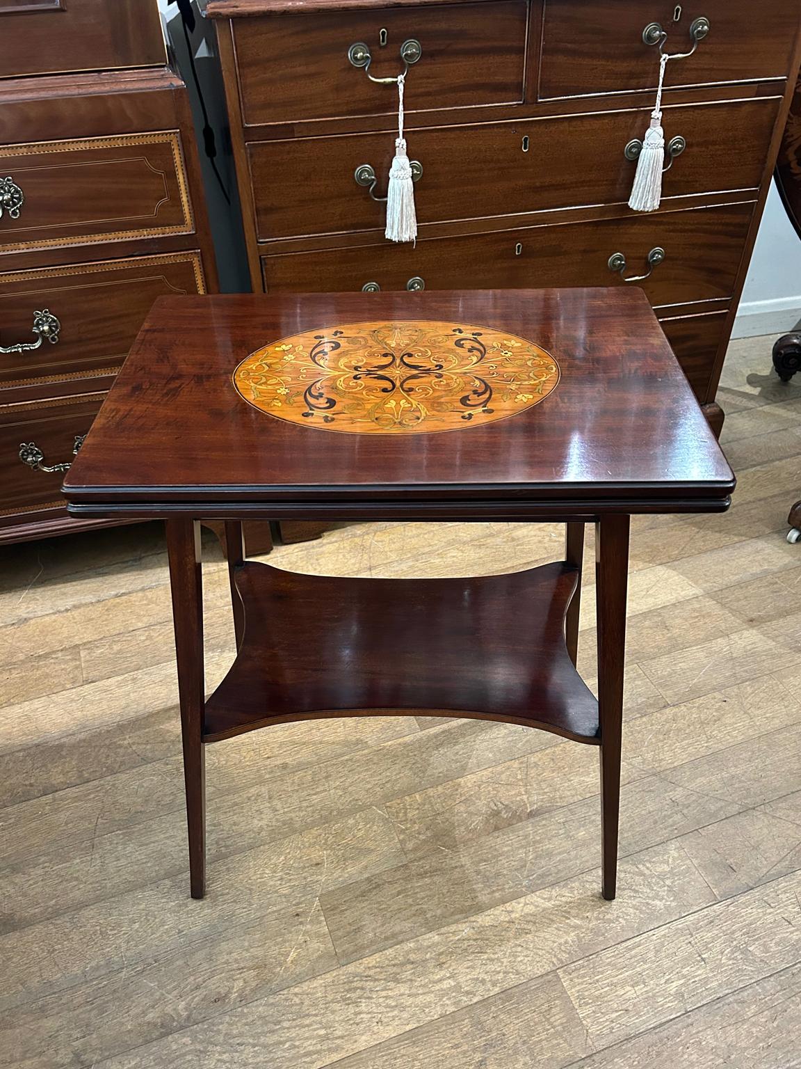 Table à cartes en acajou de très haute qualité, datant du 19e siècle, avec un plateau en marqueterie magnifiquement incrusté. Le plateau pivote de 90′ degrés pour s'ouvrir sur une table à cartes dont l'intérieur est tapissé de baize verte. Supporté
