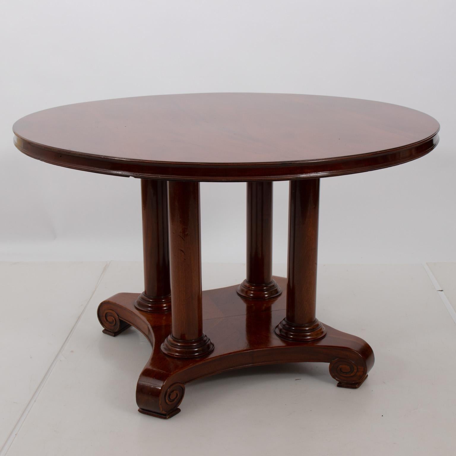 Mahogany center table in the American Empire style featuring four round columns on the base along with scrolled feet, circa 1880s. Please note of wear consistent with age including scratches and chips.