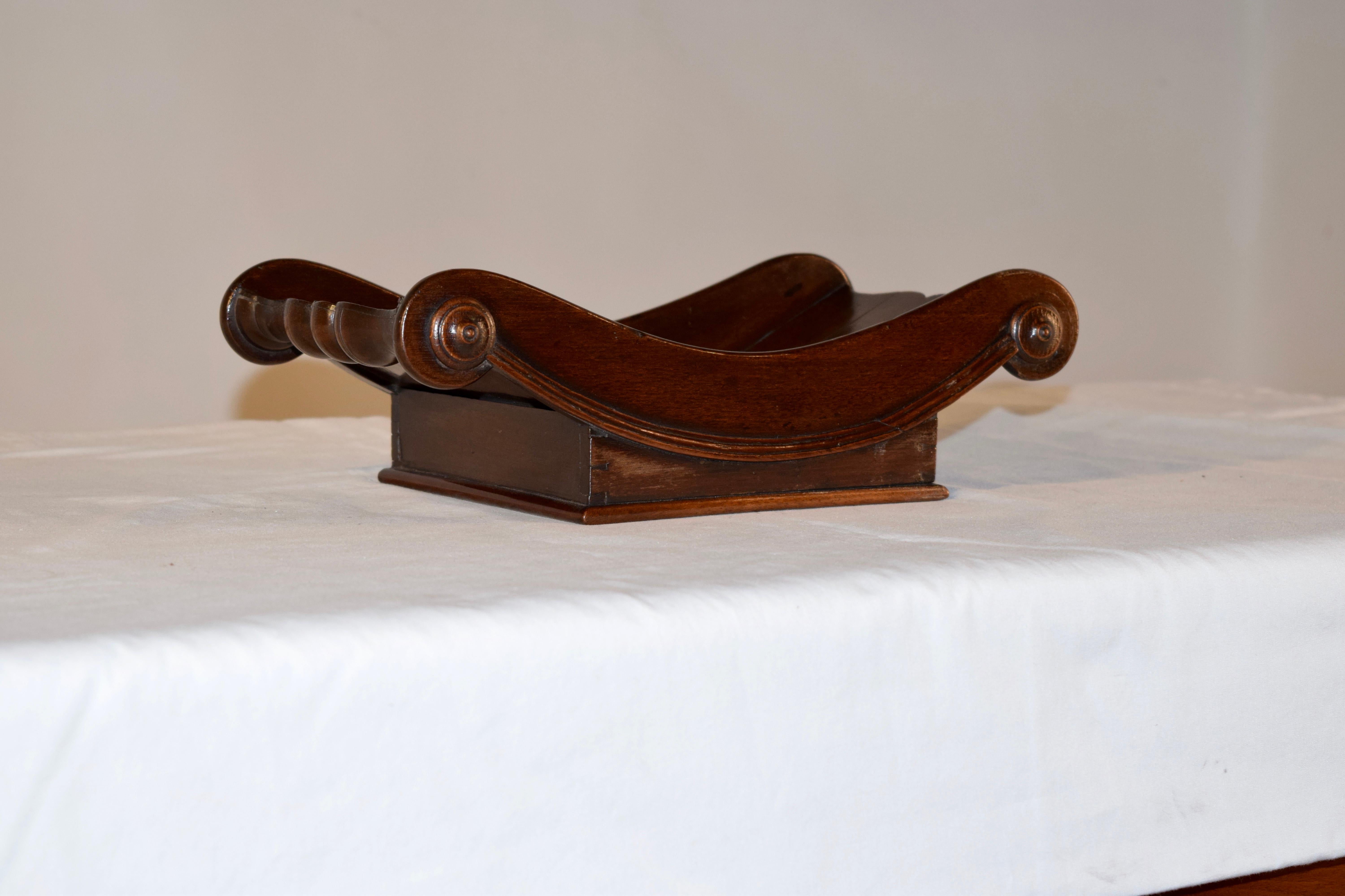 19th century mahogany cheese cradle from England with a sleigh shaped dish over a square base. The edges end gracefully in a scroll shape and molded edges.