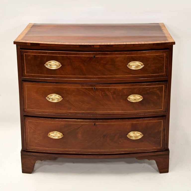 A good Hepplewhite bowfront chest of drawers in figured mahogany with string inlay and a banded top. A lovely size for a bedroom or as a nightstand, English, circa 1820s-1830s.