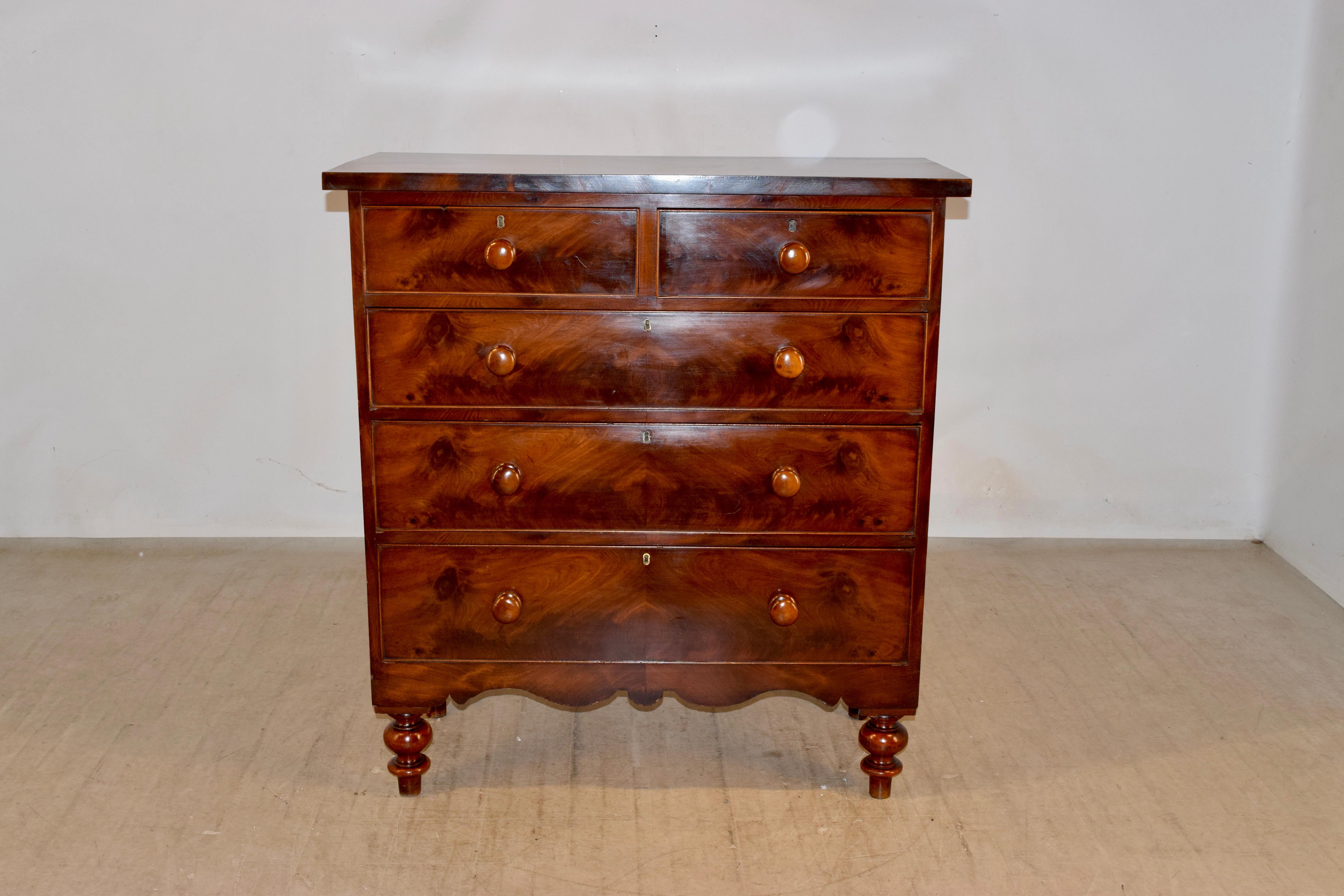 19th century mahogany chest of drawers form England with a wonderfully grained top and front. There are two over three drawers, all with wonderfully grained drawer fronts. There is a lower apron which is hand scalloped and the case is raised on hand
