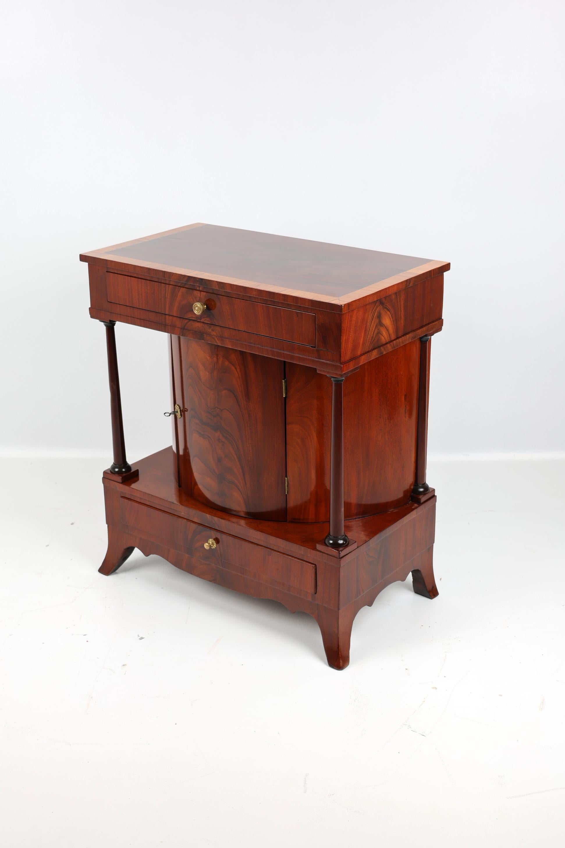 Mezzo armadio Demi Lune del XIX secolo,
Germania 1815
Mogano,

Raffinato mezzo mobile Demi Lune con colonne del periodo 1800-1815. Questa credenza antica è impiallacciata in mogano e ha due cassetti. Con una larghezza di 72,5 cm, un'altezza di 82 cm