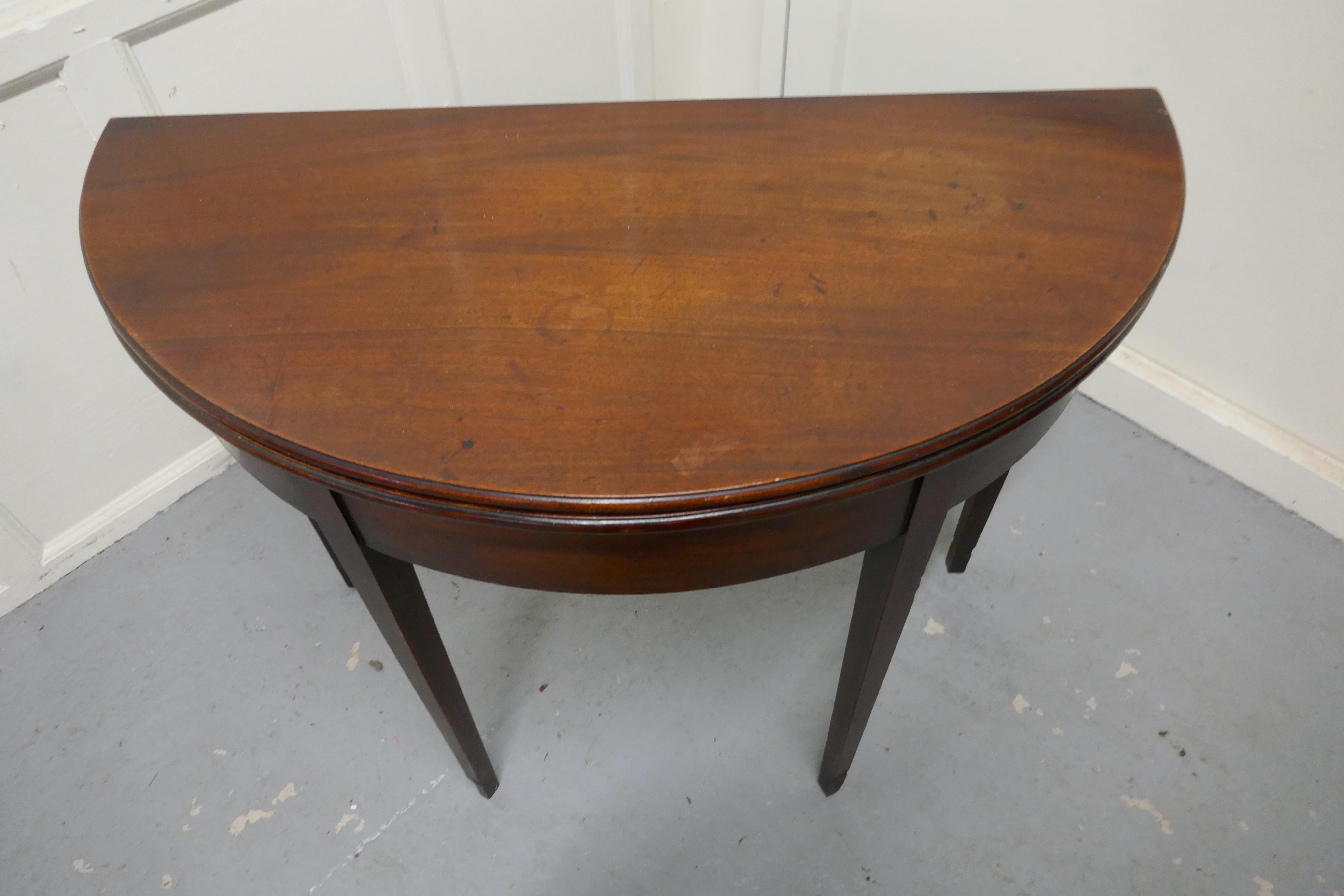 19th century mahogany demilune turn over top tea table.

The table stands on four square tapering legs, one of the back legs hinges open to act as a support when the tabletop is opened for use.

The tabletop is made from very good figured