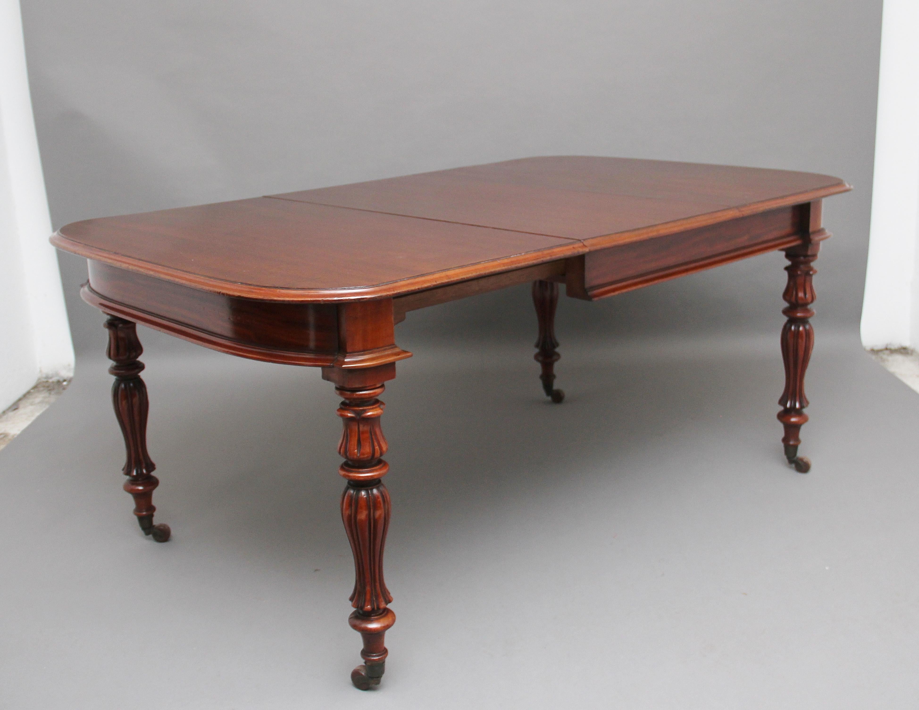19th century mahogany one leaf dining table, the solid moulded edge top with rounded corners above a deep frieze with moulded edge, supported on elegant carved turned legs with carved tulip design at the top of the leg, terminating on brass caps and