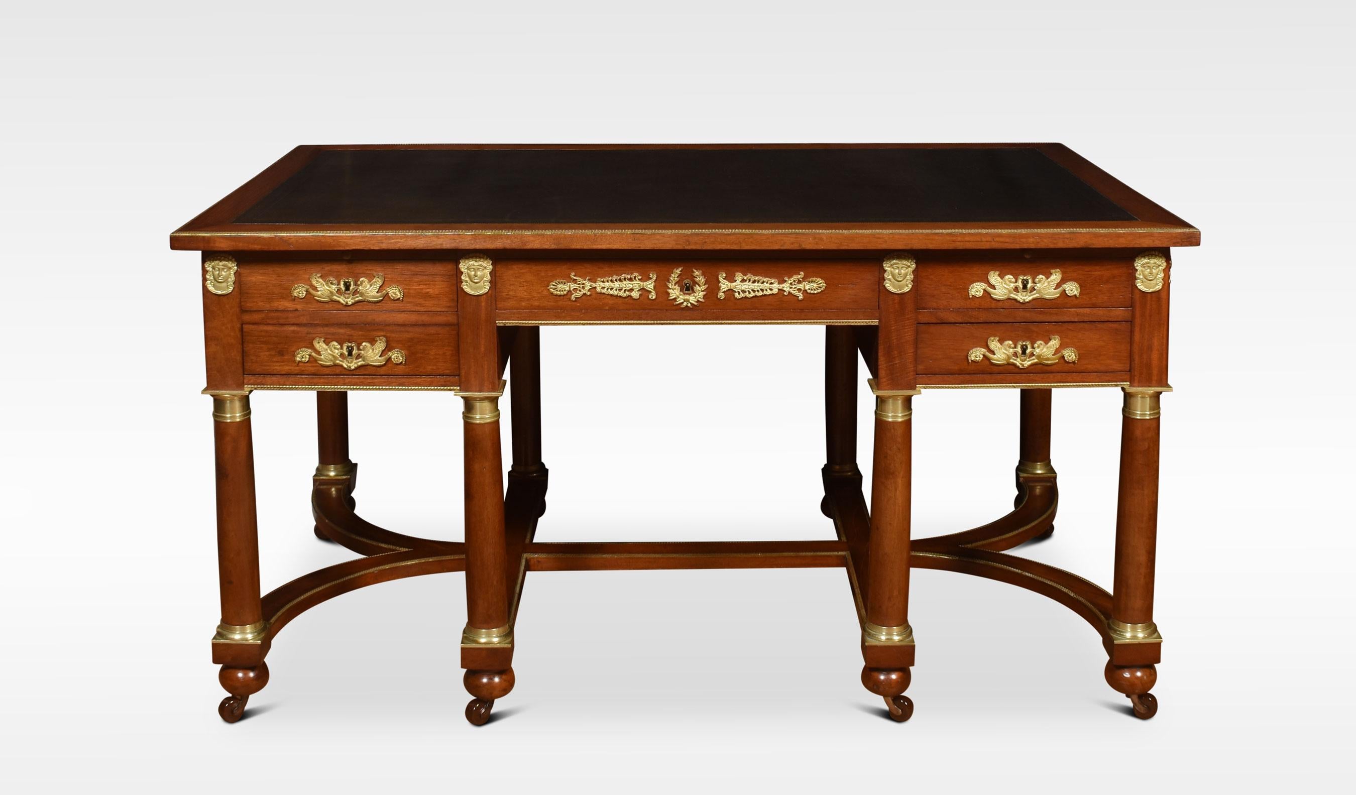 French mahogany and gilt metal mounted desk. The large rectangular mahogany top with inset leather writing surface with Greek Key border. To the frieze fitted with five drawers with opposing faux drawers. All raised up on circular turned