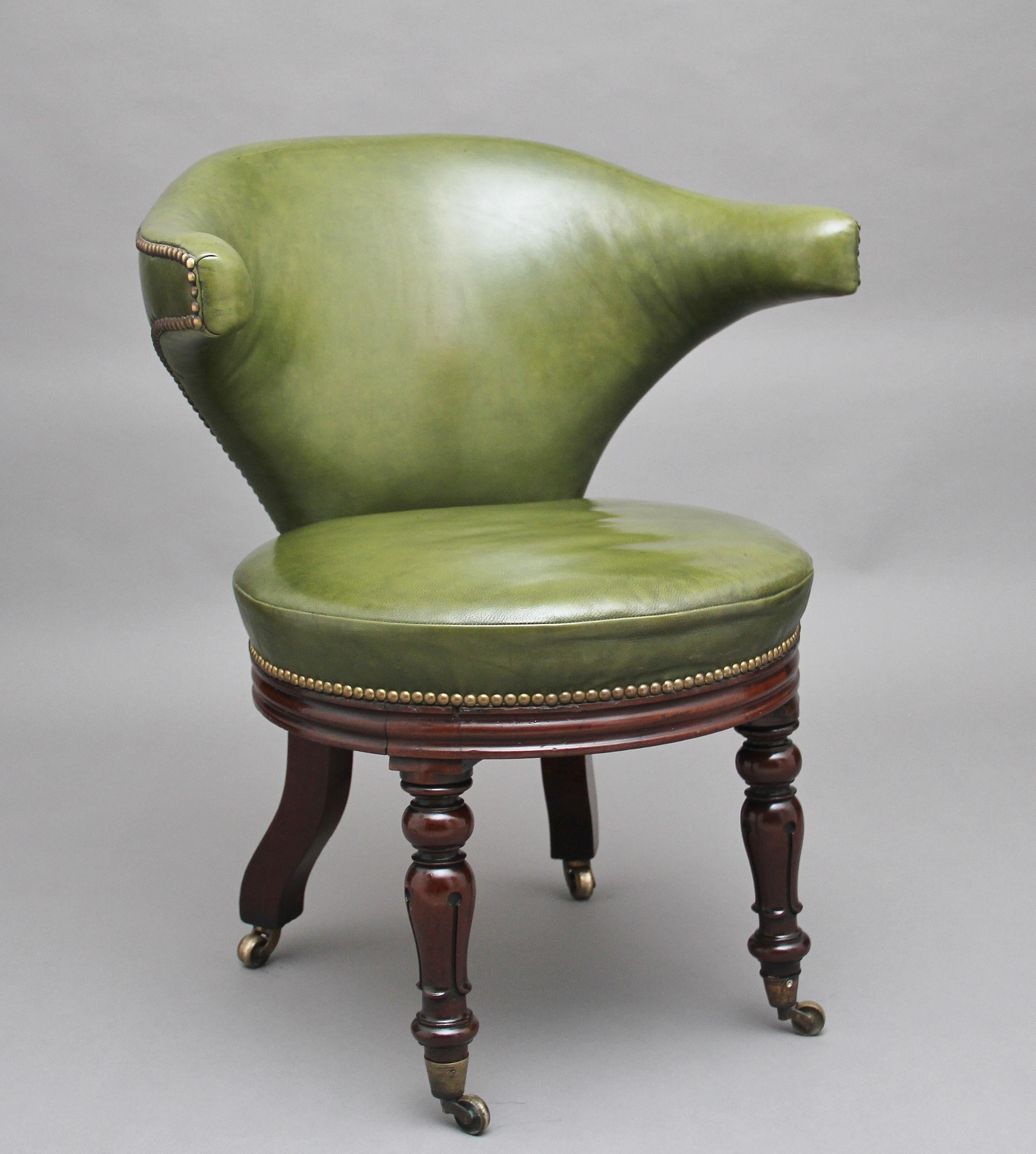 A lovely quality 19th century mahogany and green leather desk chair, having tapered and padded wing backs with brass stud decoration above a circular padded leather seat and channeled apron, raised upon incised baluster front legs and back swept