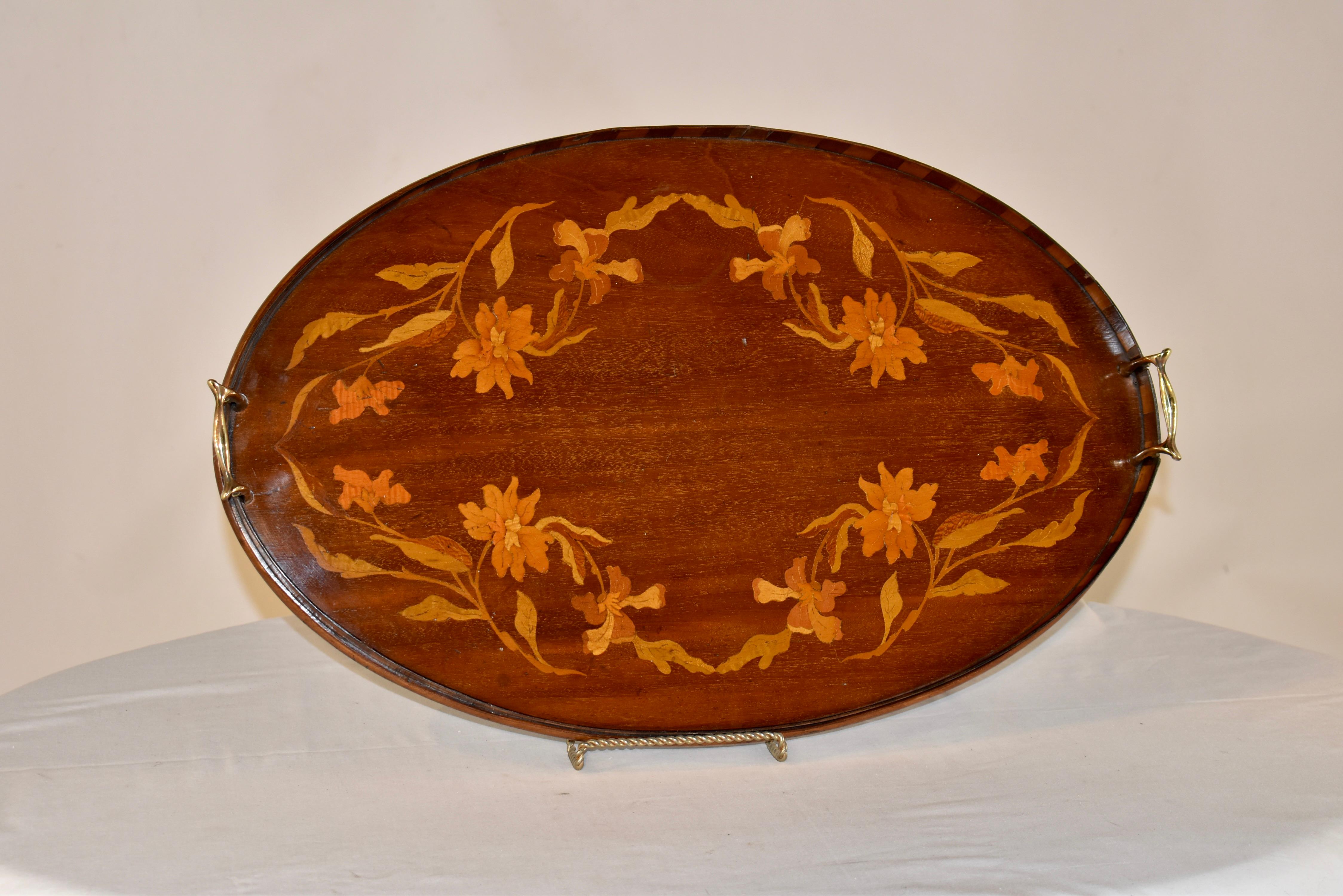 19th century mahogany tray from England inlaid in a lovely pattern with florals and vines. The tray has a gallery, which is in a lovely dark and light mahogany contrast, for added design interest. The handles are hand cast brass.