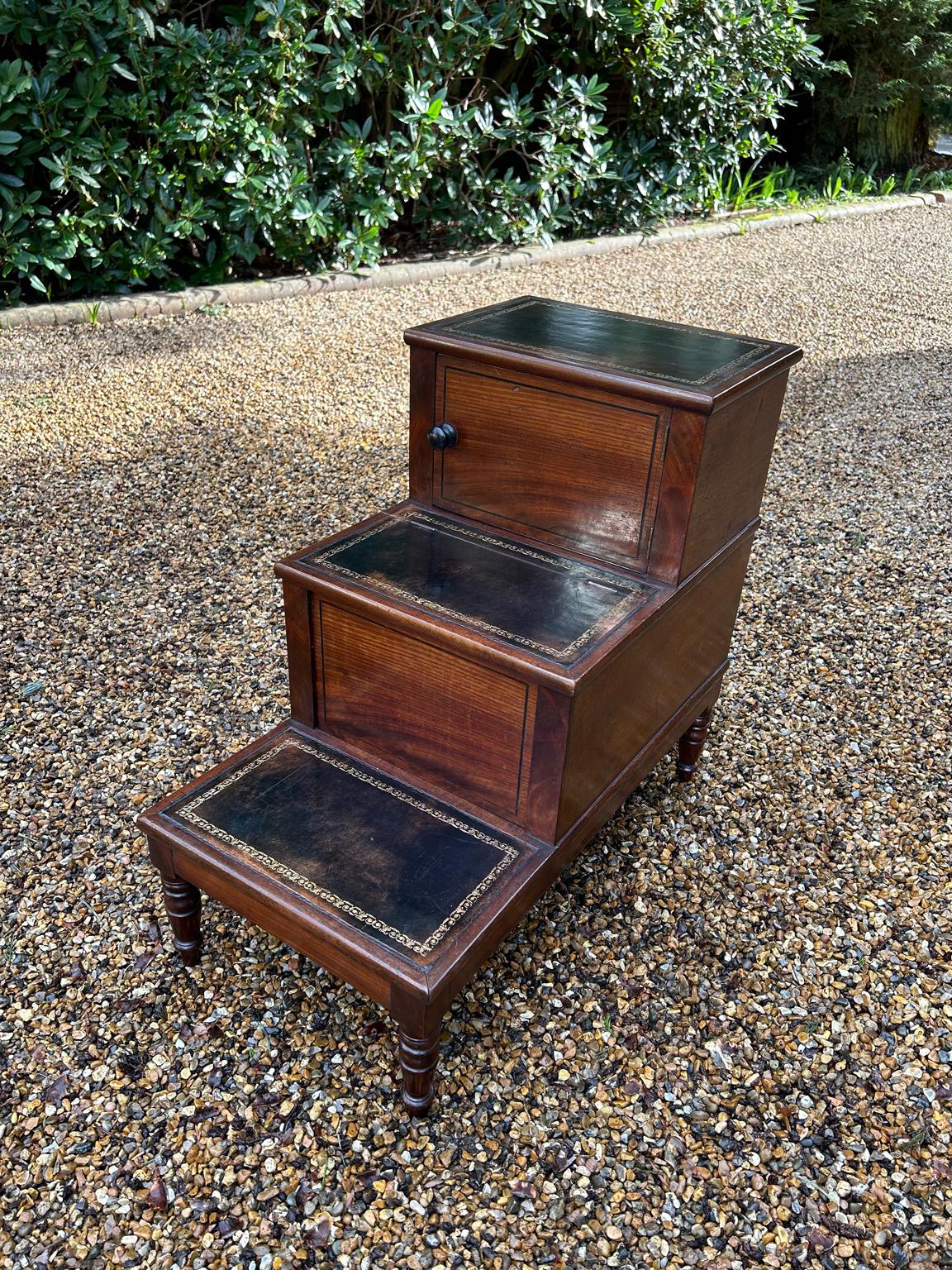 A very good quality 19th Century Mahogany Library / Bed Steps with three steps each finished in a dark leather with gold tooling. The top step with wooden turned knob opens to a small cupboard space, the middle step has a fitted cupboard inside, the