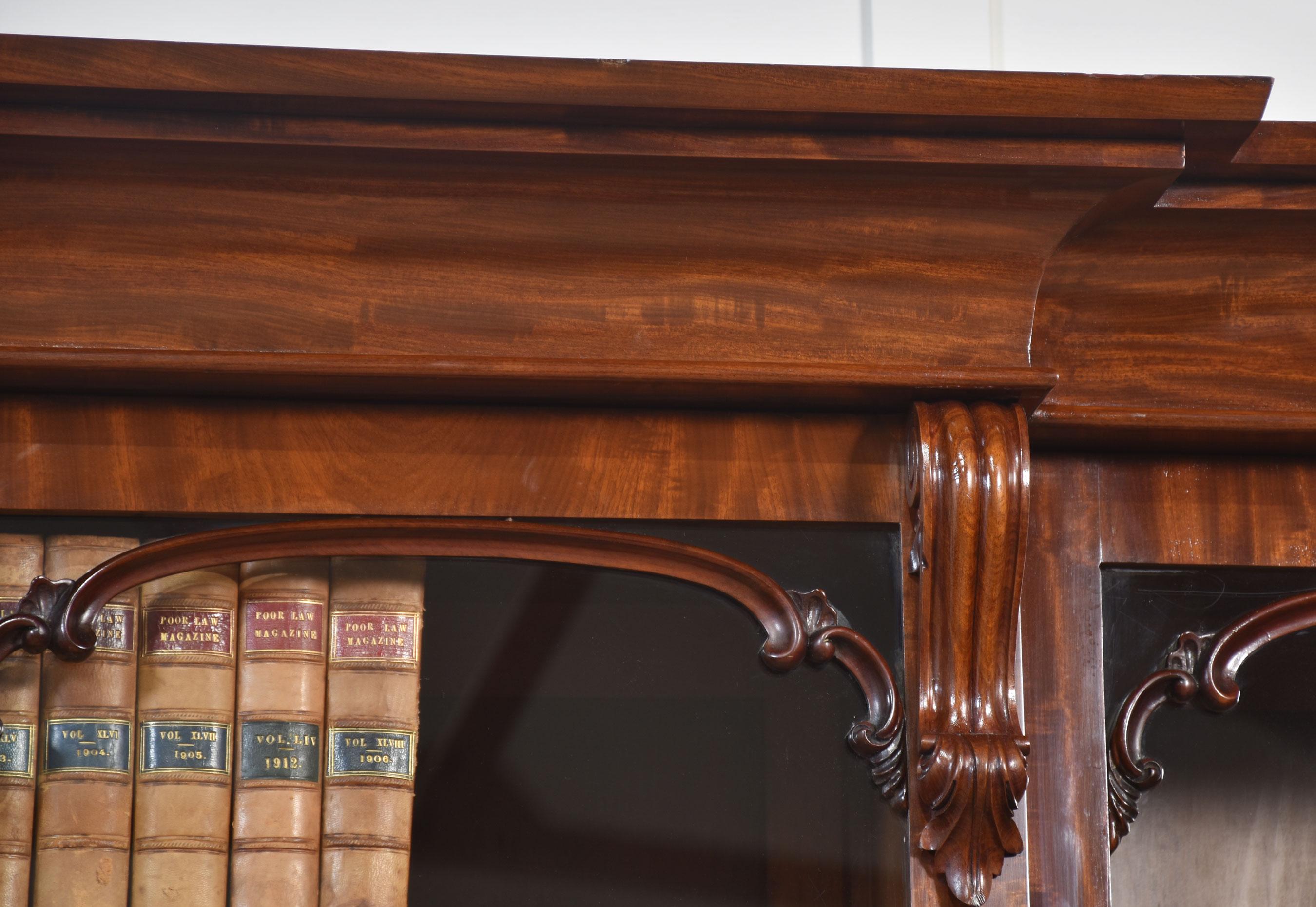 Libreria in mogano con ante a ribalta. La cornice a gradini e modanata sovrasta le quattro porte vetrate superiori, che si aprono per rivelare un interno a ripiani regolabili. La sezione di base ha quattro cassetti sopra quattro porte a canale ben