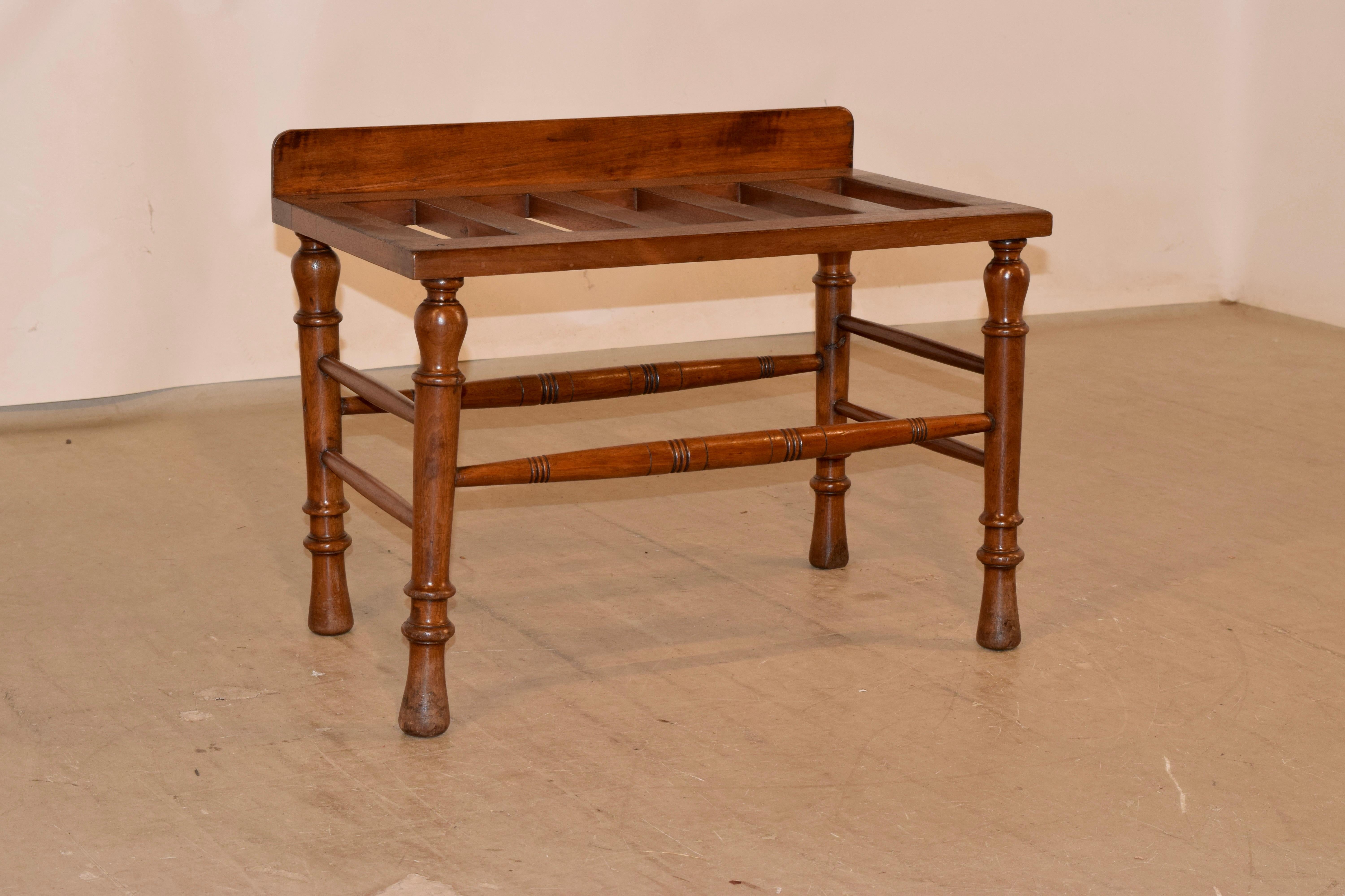 19th century mahogany luggage stand from England with a backsplash and slatted top over hand turned legs, joined by hand turned stretchers.