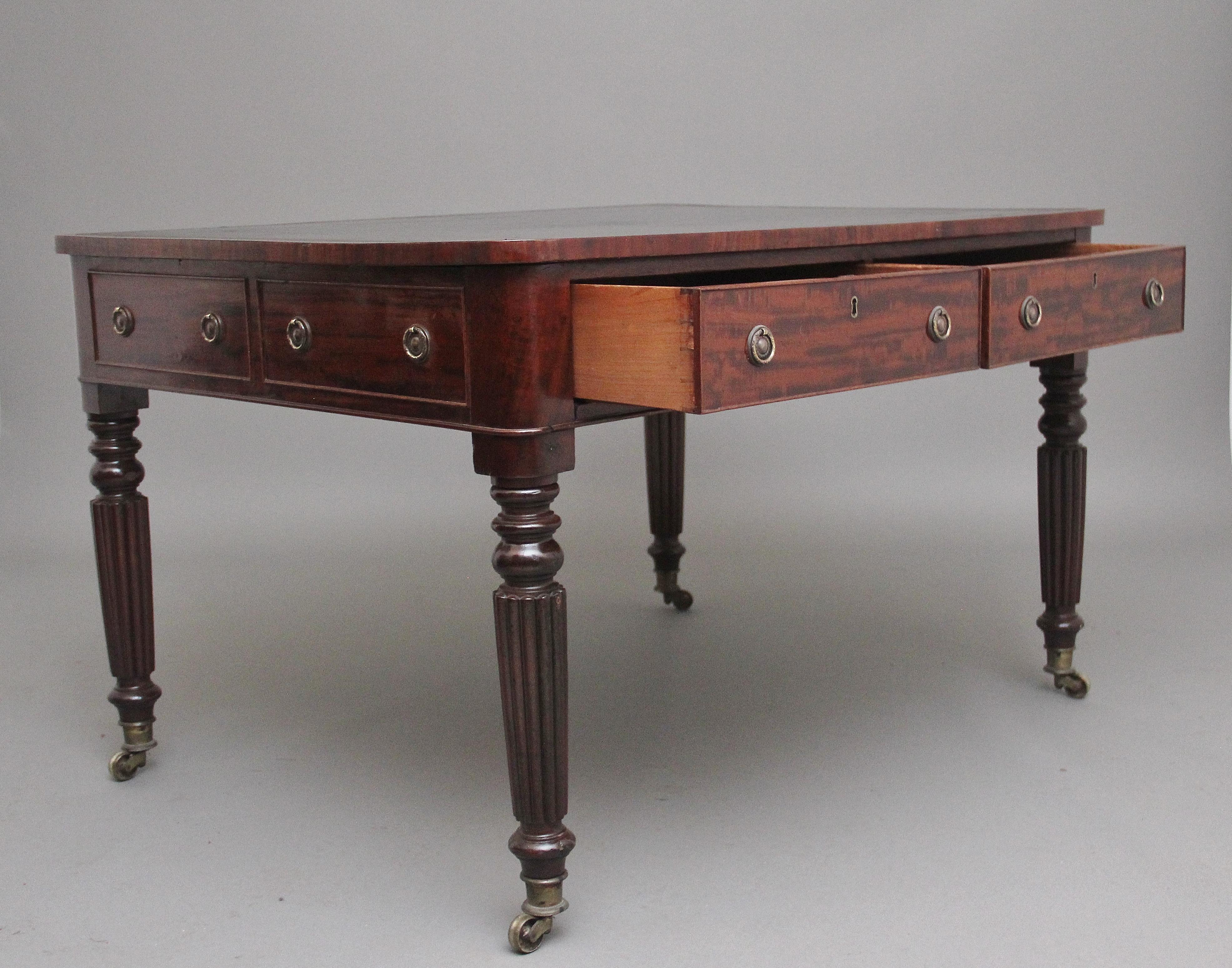 19th century Mahogany partners writing table, having a black leather writing surface decorated with gilt and blind tooling , two drawers either side with the original brass ring handles, with faux drawers on each end, supported on turned and fluted