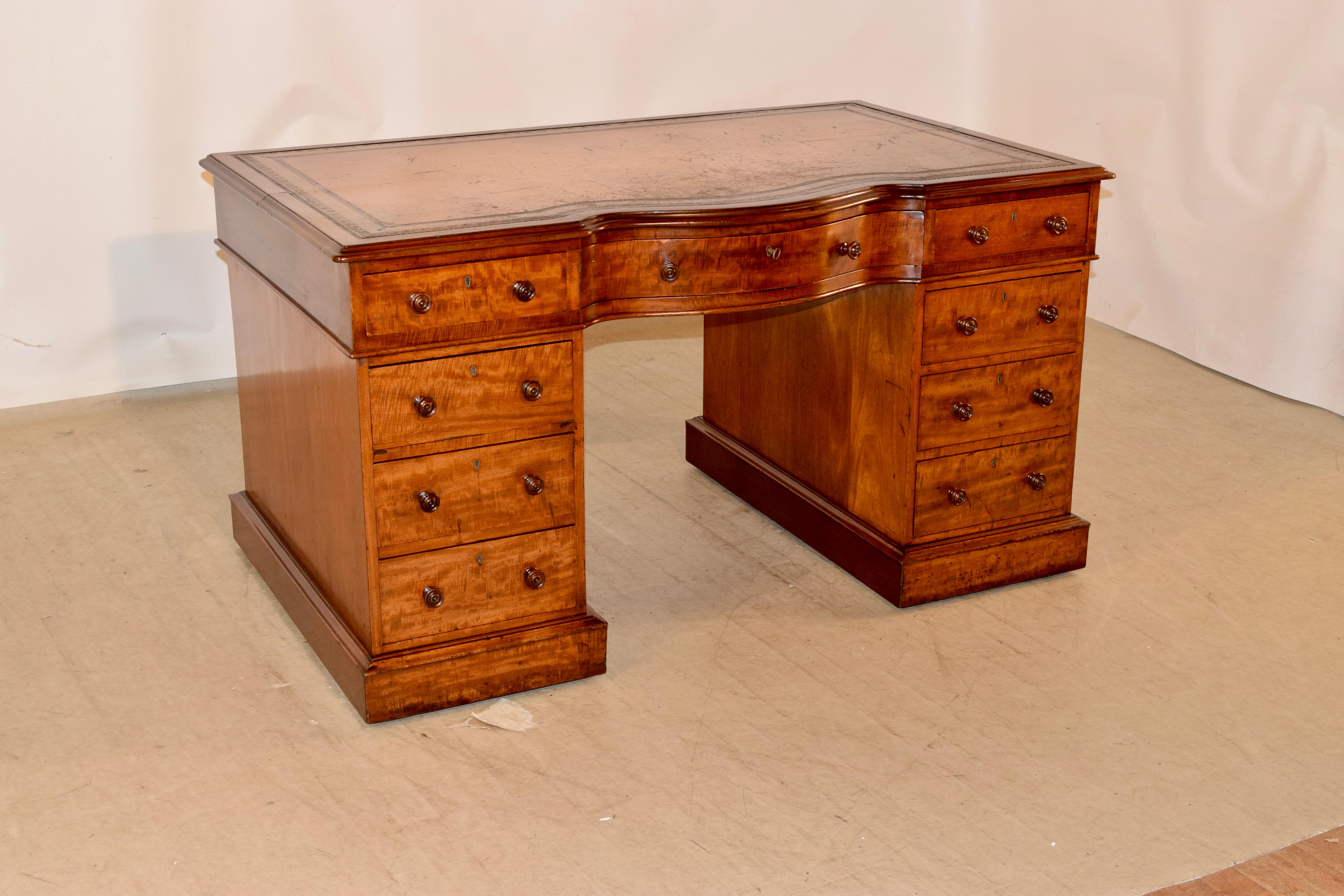19th century English pedestal desk made from mahogany. The top is covered in the original tan leather, which has aged beautifully, and is banded by a shaped mahogany border. The desk is in a wonderfully grained and colored mahogany, which has aged