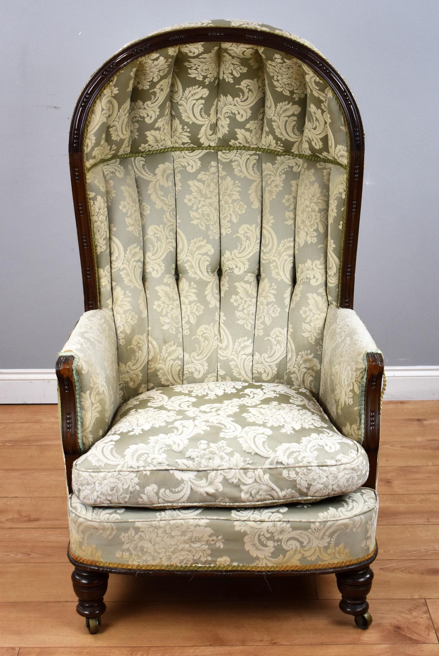 19th century mahogany porters chair in good condition, upholstered in a floral fabric, deep buttoned to the inside, stands on small turned legs on castors to the front and splayed feet on castors to the back.