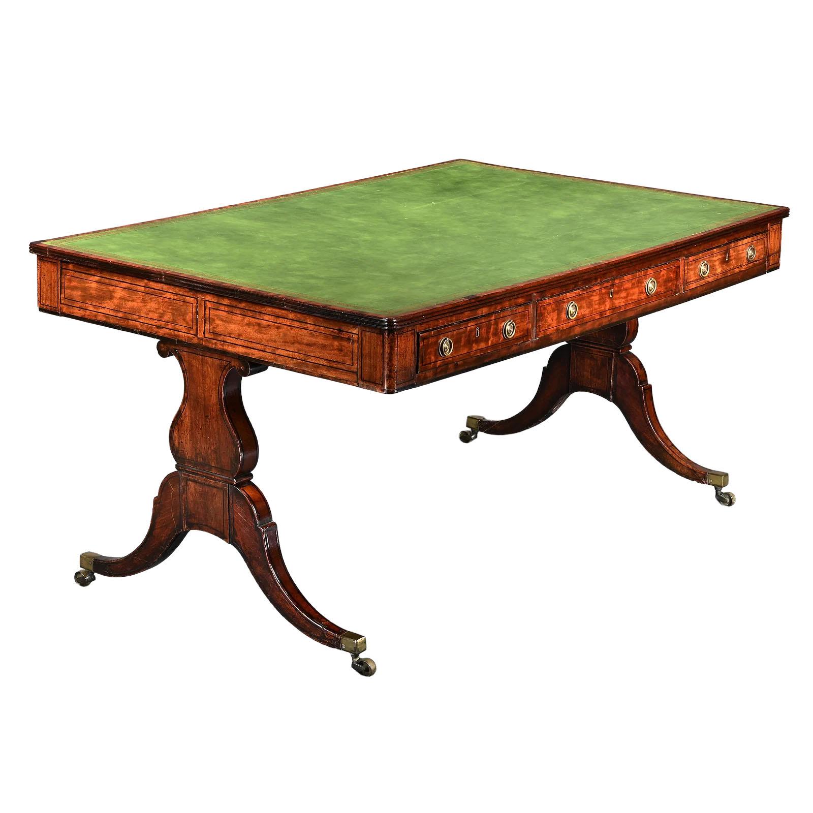 An exceptional mahogany Regency writing or library table, featuring a rectangular green leather inset top tooled with an elegant border of gilt-scrolled acanthus flower heads and a subtly worn patina that attests to its age. Three aligned drawers on
