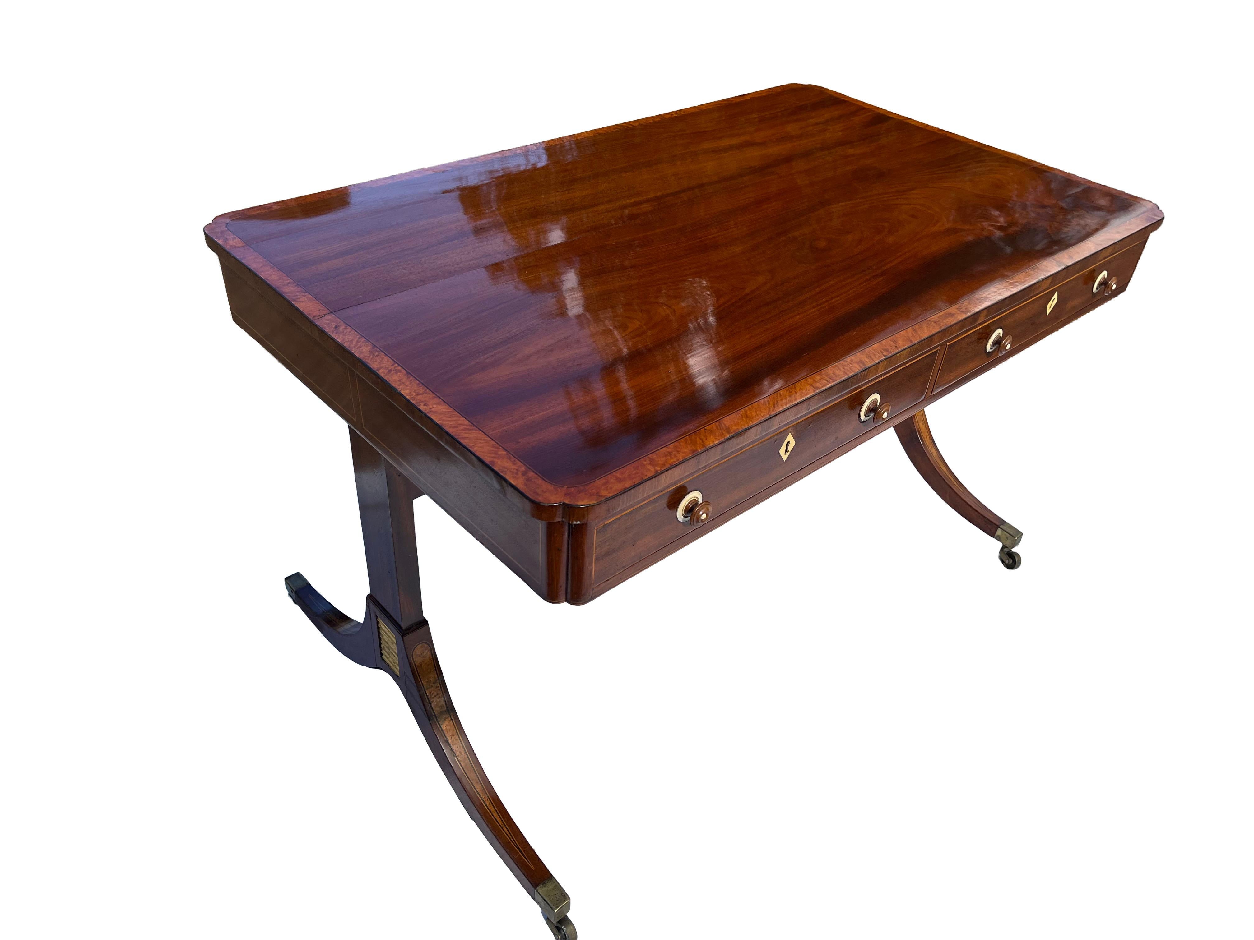 An exquisite writing table featuring a figured mahogany top adorned with charming clover-leaf corners. The table’s delicate proportions and pleasing aesthetics are further enhanced by its cross-banded satinwood construction and finely line-inlaid