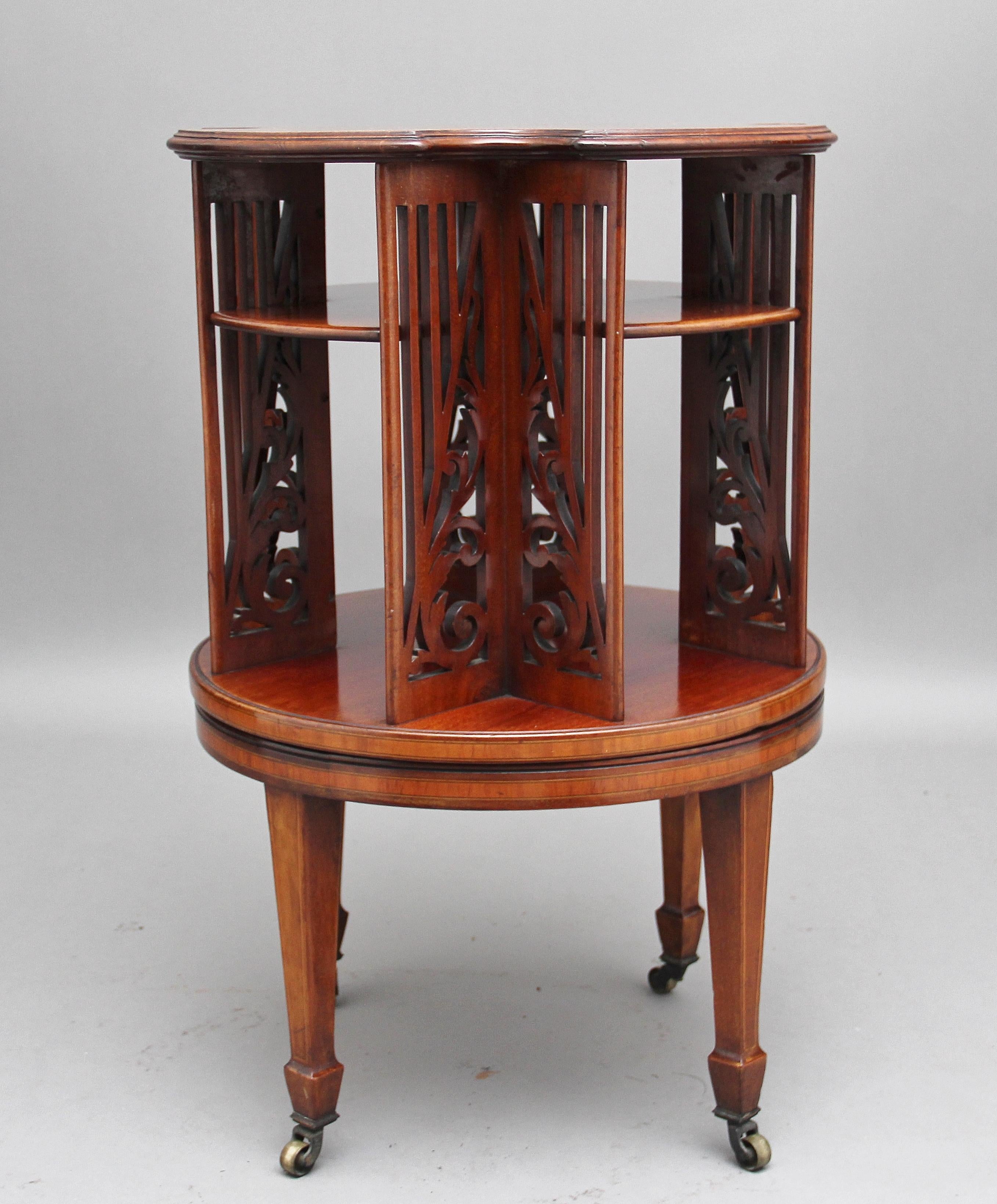 19th century mahogany, satinwood banded and further inlaid revolving bookcase of shaped circular form, the central medallion with classical and foliate scroll decoration, having pierced side panels, standing on square tapering legs ending on brass