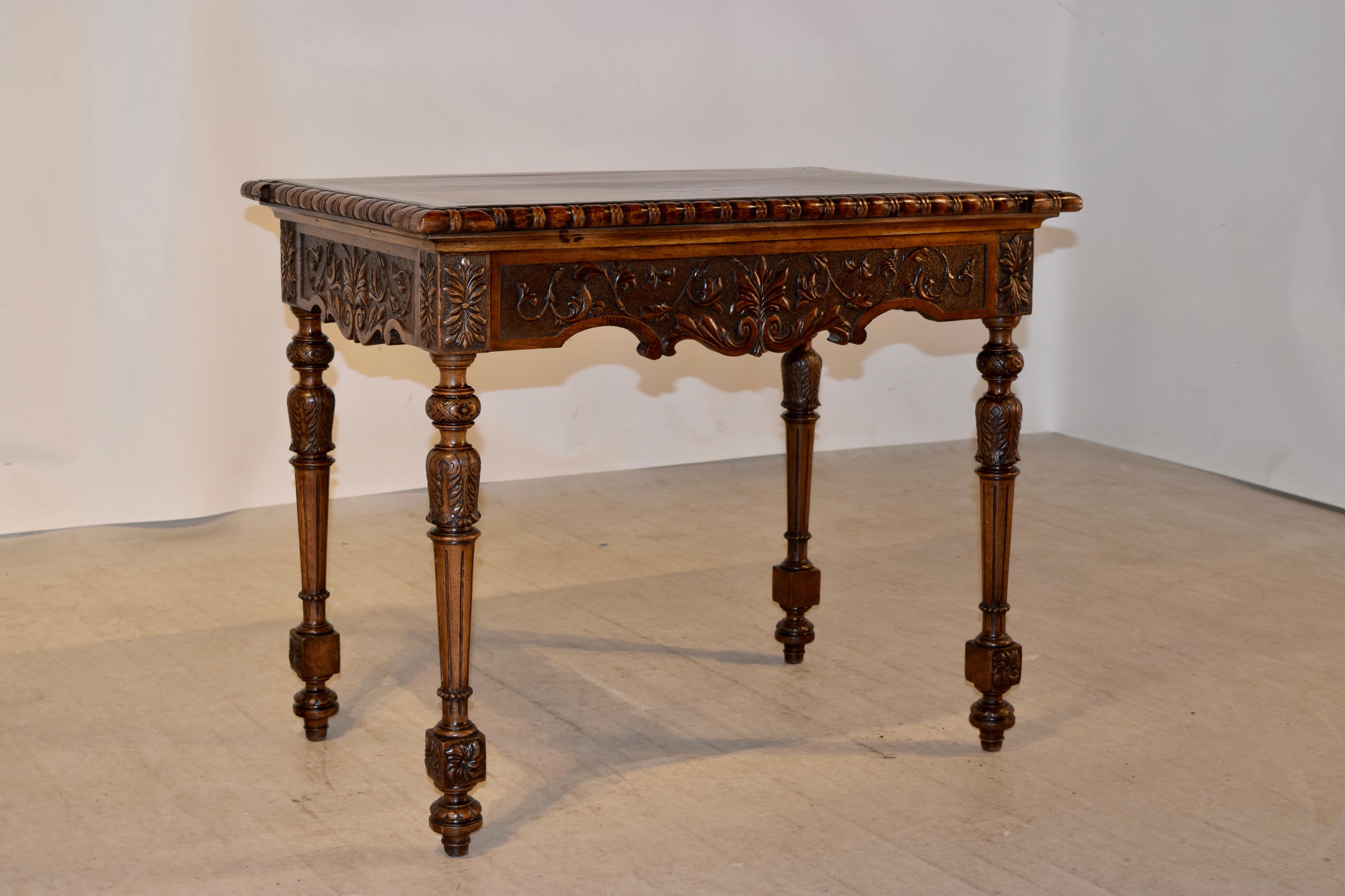 19th century mahogany side table from France with a shaped edge around the top which is hand carved decorated and beveled, following down to a carved and scalloped apron over hand-turned and reeded legs. The legs are tapered and end in carved and