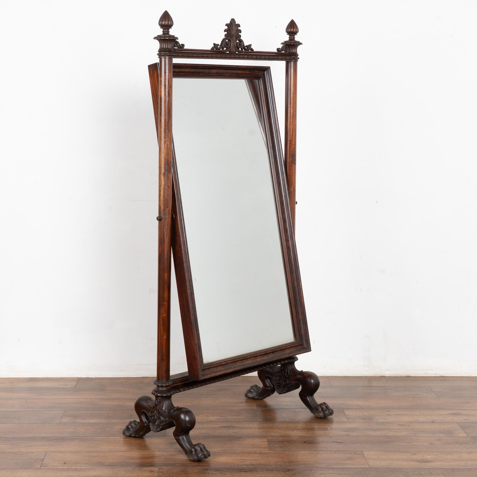 Miroir de sol réglable et inclinable en acajou, d'une hauteur de plus de 5,5 pieds.
Notez les élégants épis de faîtage et la fleur centrale qui couronnent le miroir, reposant sur des pieds de lion sculptés de manière élaborée.
Restauré, prêt à