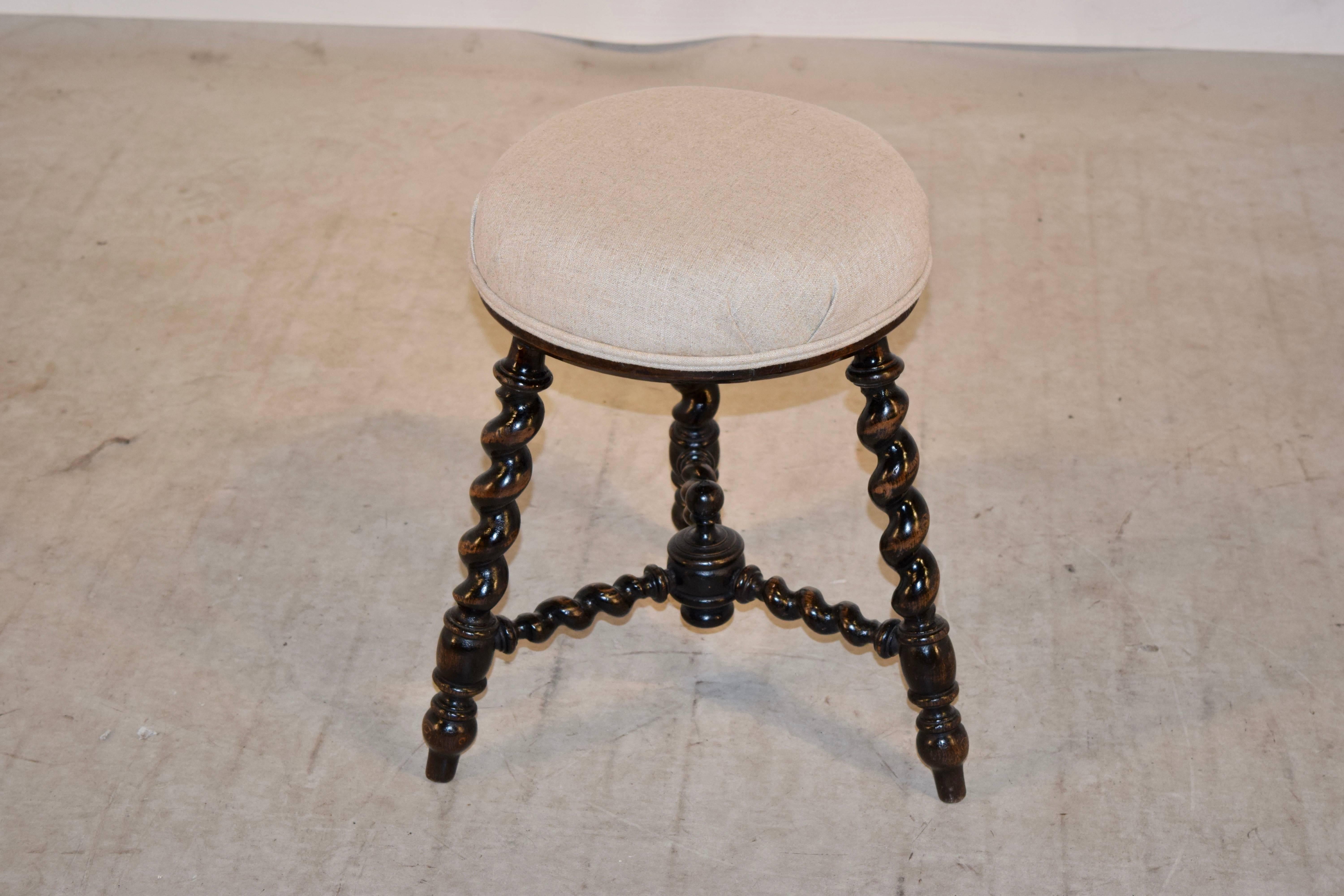 19th century English stool made from mahogany. The seat has been newly upholstered in linen and finished with a double welt decoration. The legs are hand-turned barley twist and are splayed and joined by matching stretchers.