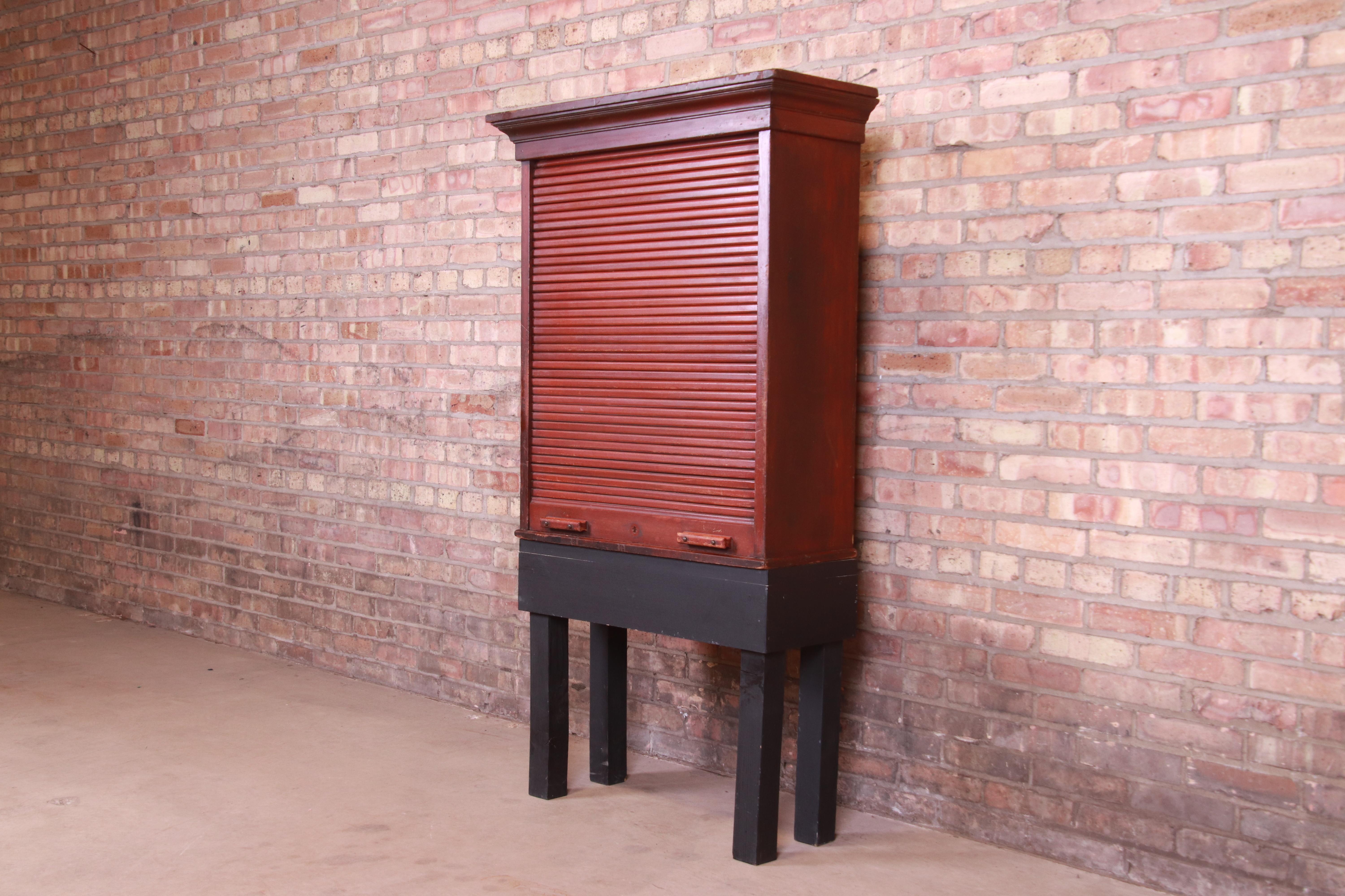 A unique Americana Folk Art railroad ticket cabinet with 92 cubbies,

USA, late 19th century

Mahogany, with roll down tambour door and black painted base.

Measures: 33