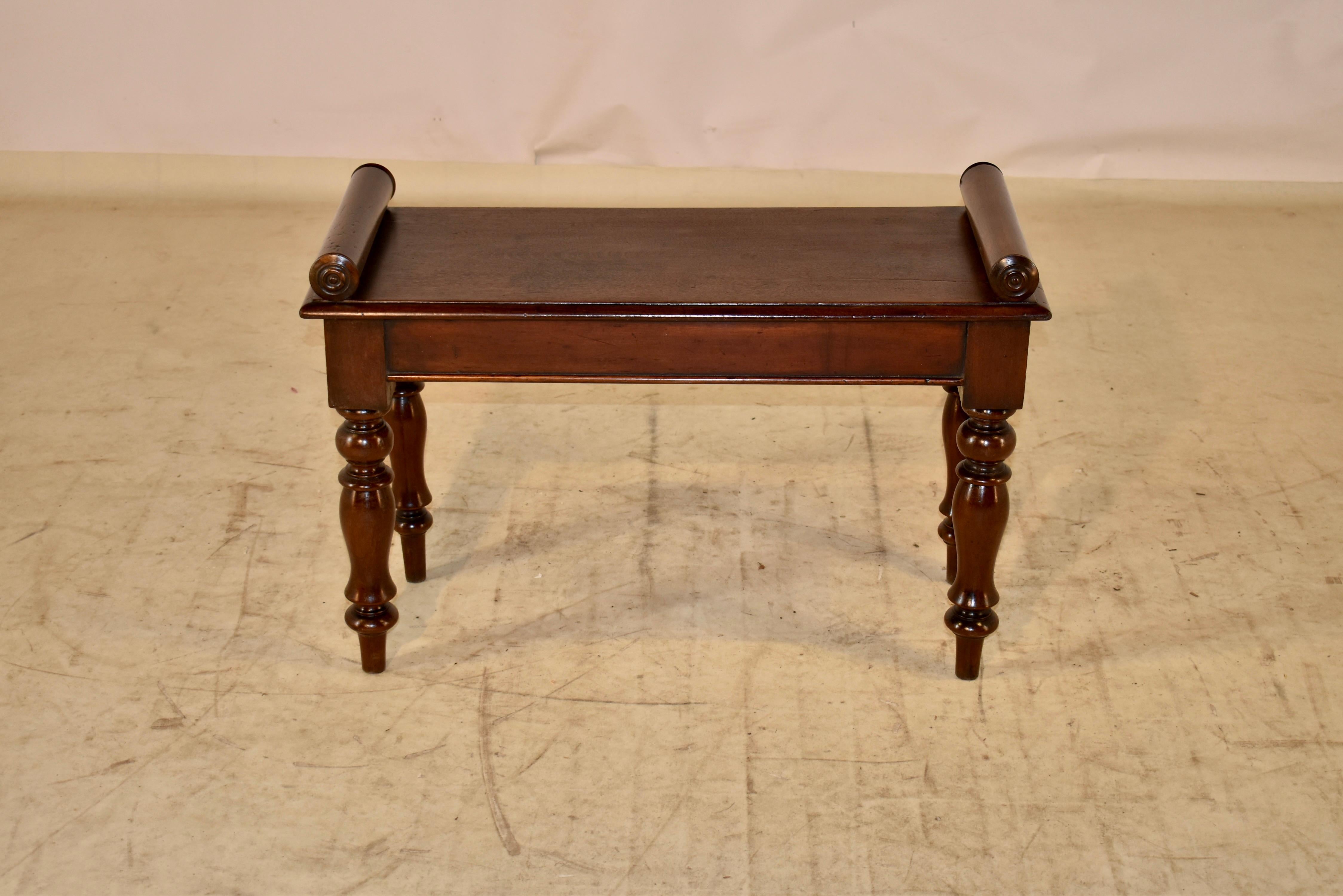 19th century mahogany window seat or small bench from England. The piece has lovely rolled arms applied to the top of the seat, which is made from a single plank and has a beveled edge. The apron is simple and has a beaded edge, and the bench is