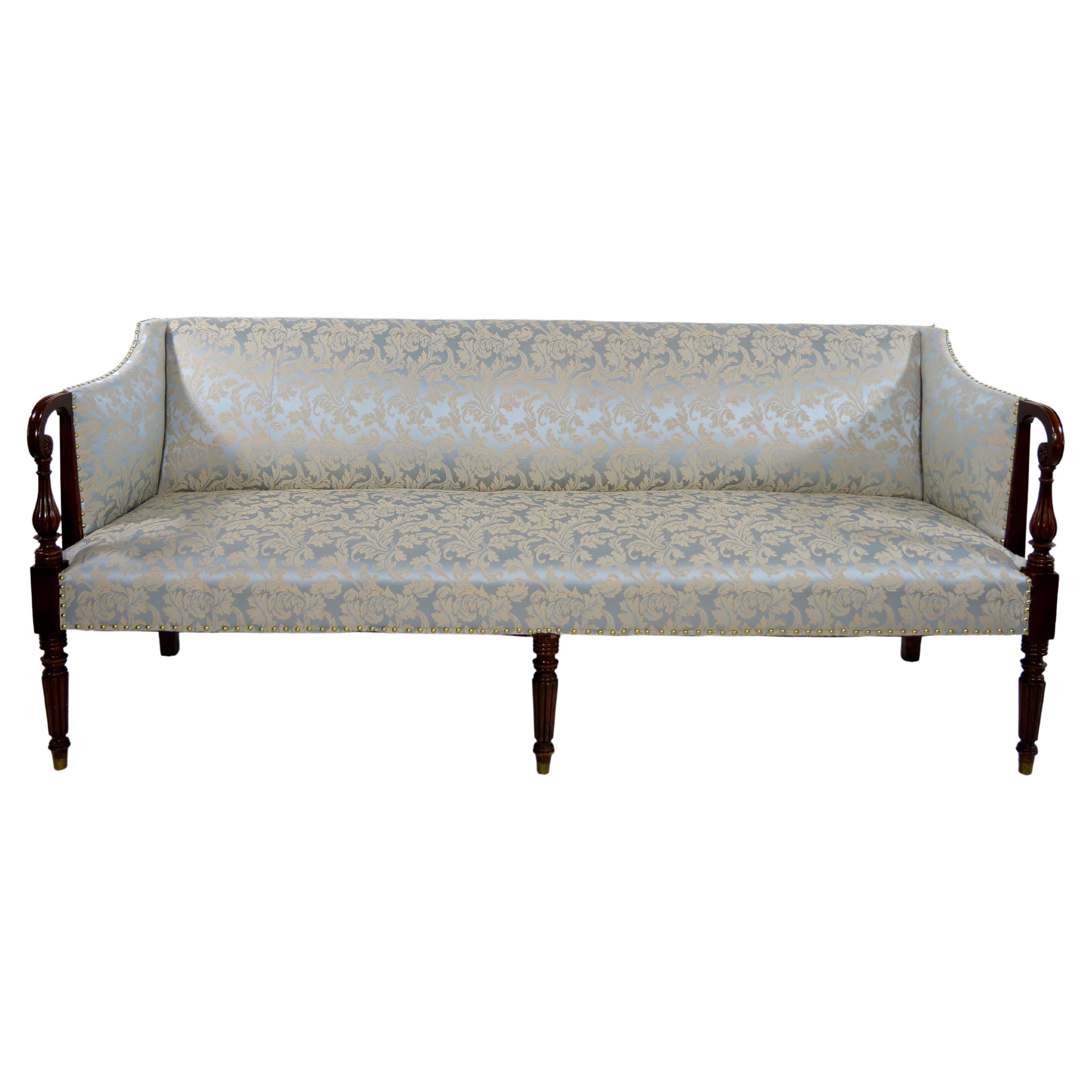 Exquisite mid 19th century mahogany wood framed Federal Sheraton style upholstered sofa. The sofa features hand carved in the Sheraton style design and upholstered side arm rest standing on five hand carved mahogany legs. The sofa is in great