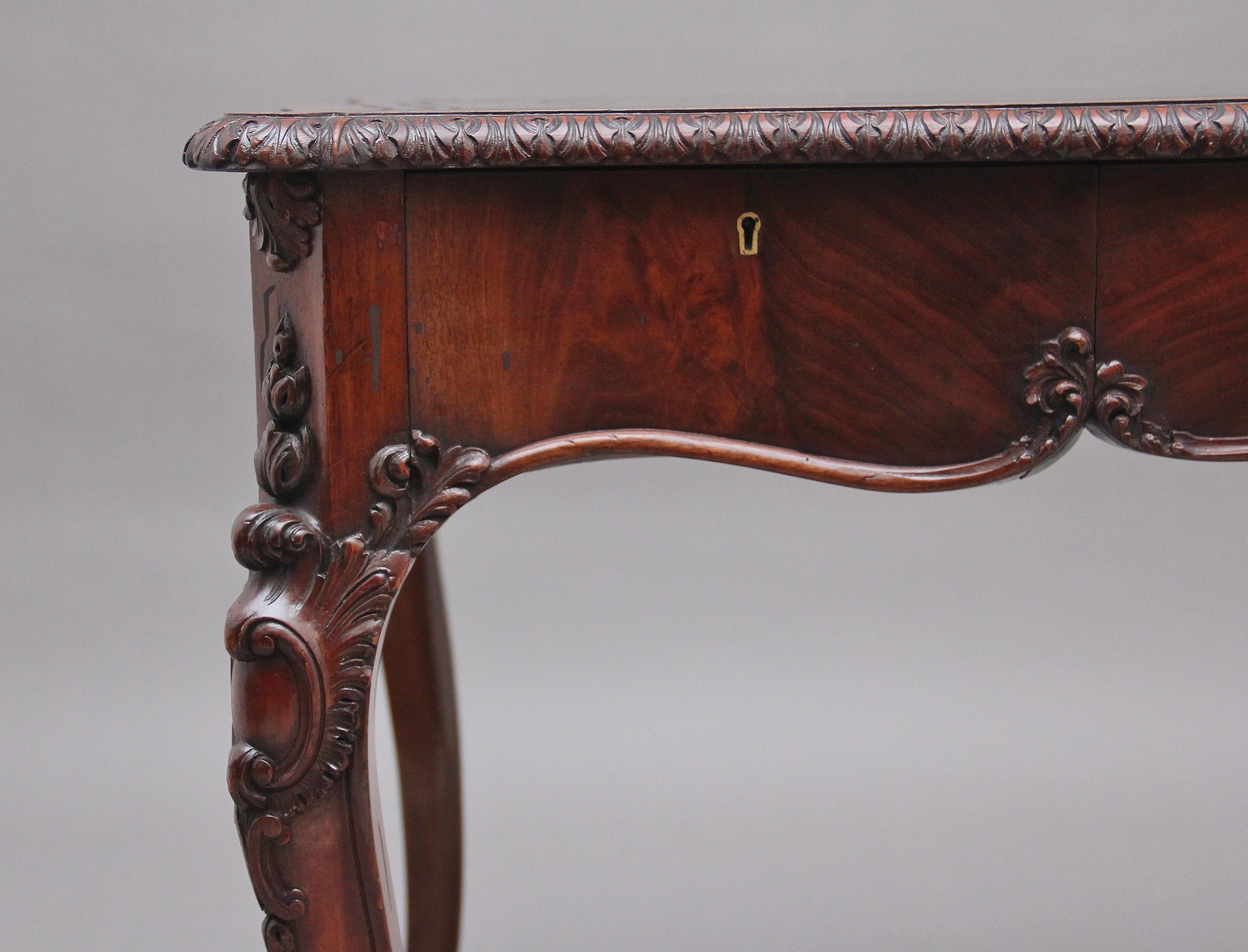 19th century mahogany writing table, having a shaped and crossbanded top with a green leather writing surface decorated with blind and gold tooling, a chrisp carved moulded edge, a mahogany lined frieze drawer below with carved detail on the bottom