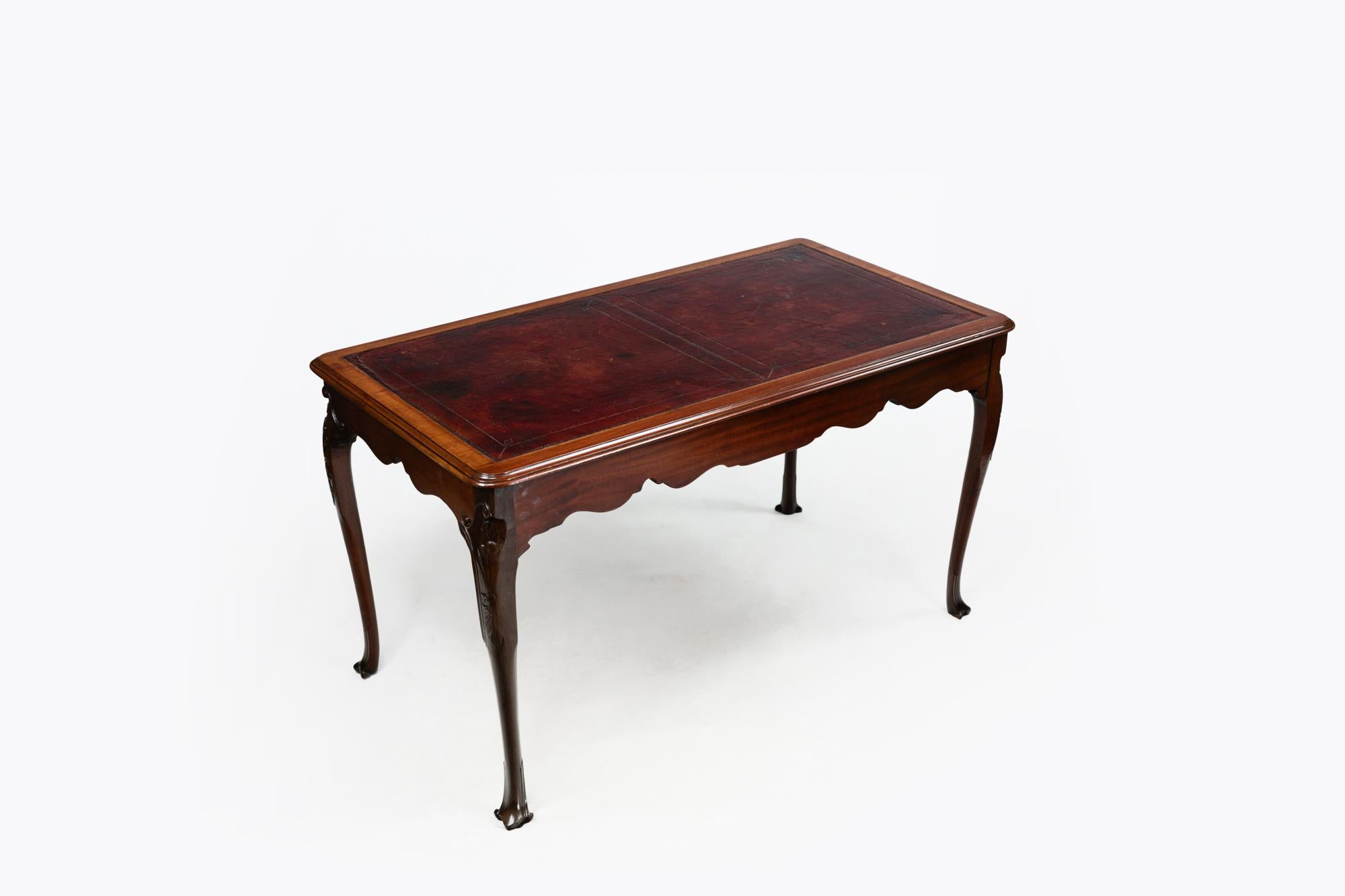 Table à écrire du 19e siècle en acajou avec plateau en cuir tolé. Soutenu par des pieds cabrioles ornés de motifs sculptés de rinceaux et de feuillages, se terminant par des pieds trilobés sculptés.