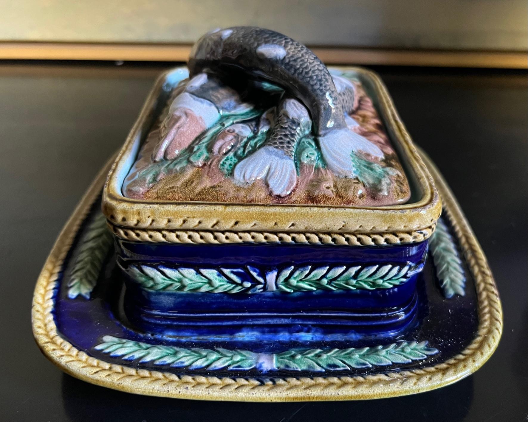 Majolika-Sardinendose mit Deckel, hergestellt in England im späten 19. Jahrhundert. Der Deckel ist in Hochrelief mit Fischen auf einem Bett aus senffarbenem Seetang geformt.  Die Dose ist von Hand kobaltblau bemalt und mit grünen Blättern verziert.