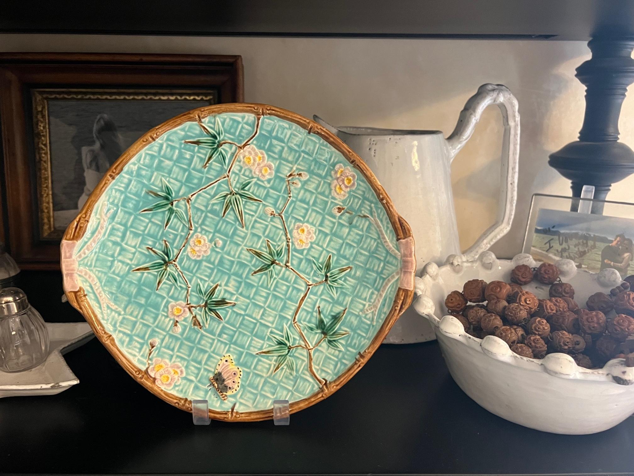 English majolica platter, attributed to Simon Fielding of Railway Pottery,  Sutherland Street, Stoke-on-Trent. The platter has a bamboo weave background covered in prunus and a butterfly, edged with bamboo and tied on each end with pink bows.