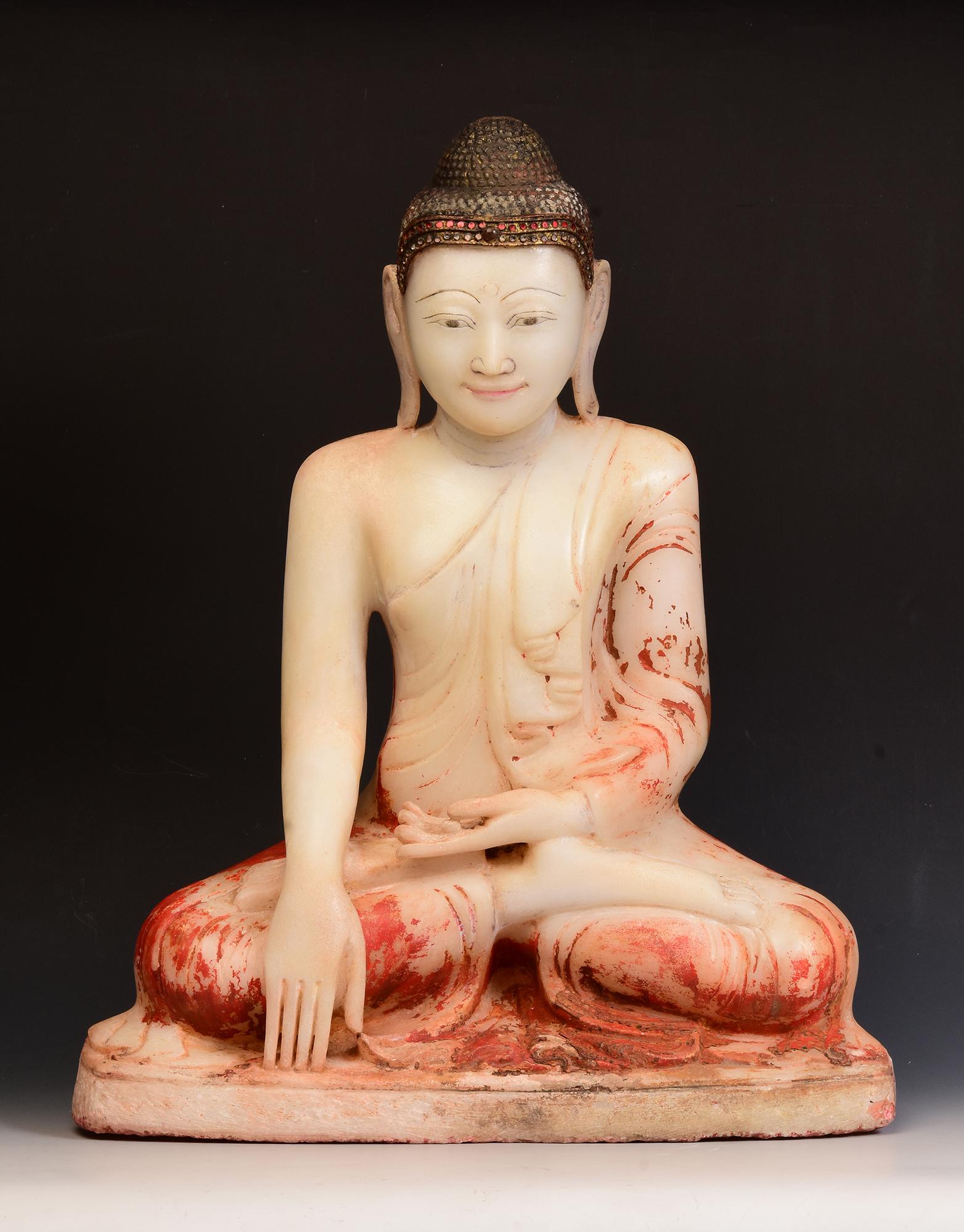 Antique Burmese alabaster Buddha sitting in Mara Vijaya (calling the earth to witness) posture on a base, with inlay of colorful glass pieces on the headband.

Age: Burma, Mandalay Period, 19th Century
Size: Height 57.8 C.M. / Width 46.8 C.M. /