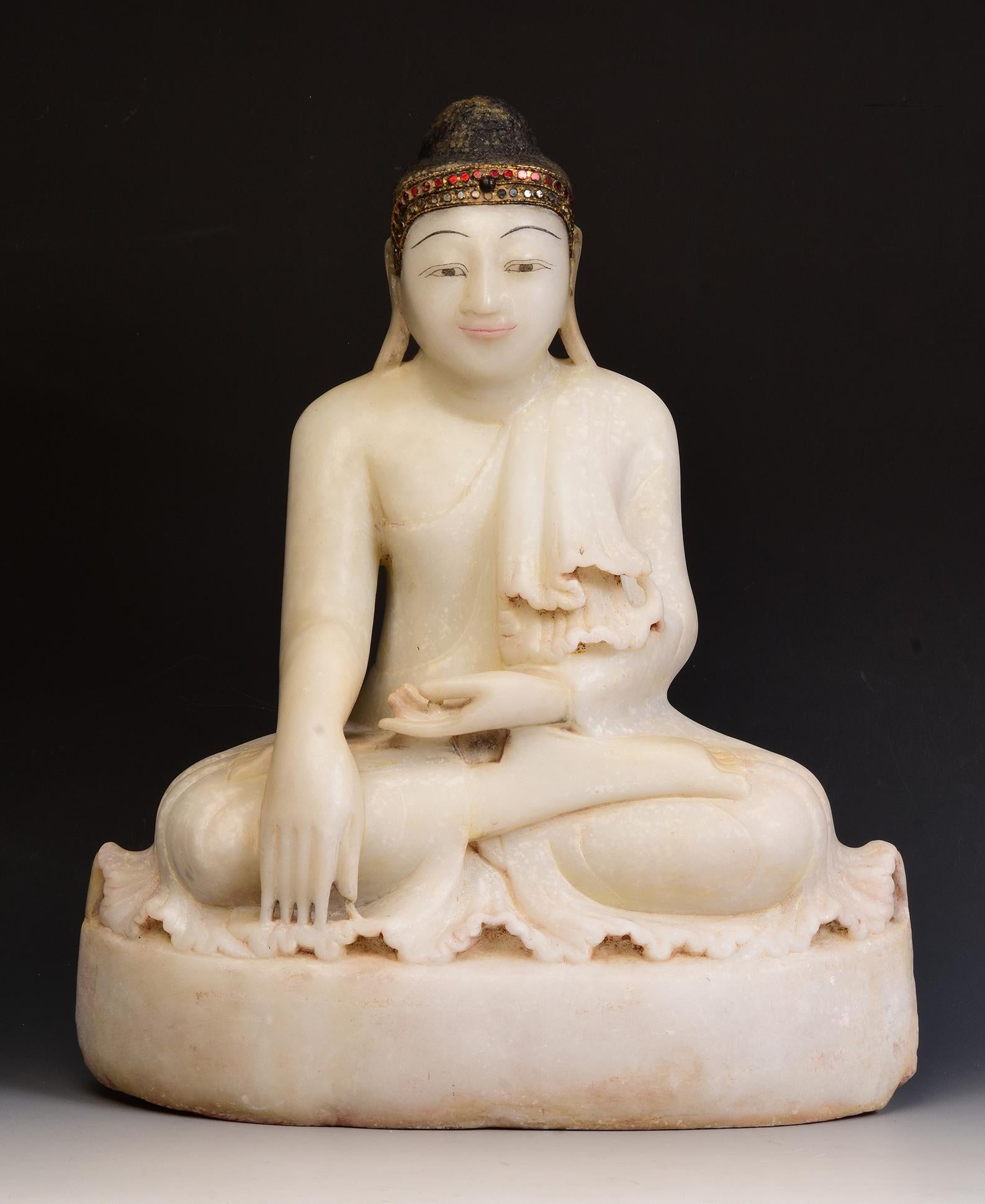 Antique Burmese alabaster Buddha sitting in Mara Vijaya (calling the earth to witness) posture on a base, with inlay of colorful glass pieces on the headband.

Age: Burma, Mandalay Period, 19th Century
Size: Height 54 C.M. / Width 44.2 C.M. / Depth