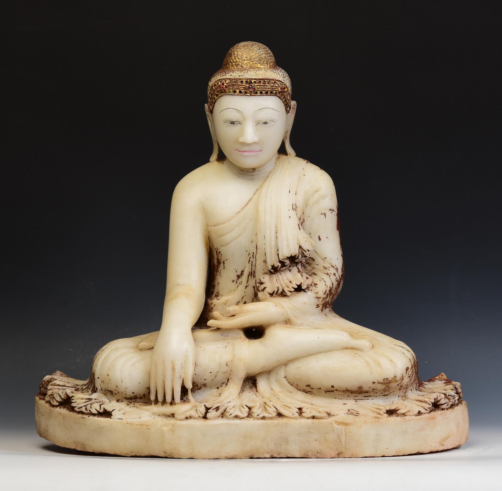 Antique Burmese alabaster Buddha sitting in Mara Vijaya (calling the earth to witness) posture on a base, with inlay of colorful glass pieces on the headband.

Age: Burma, Mandalay Period, 19th Century
Size: Height 52.3 C.M. / Width 55 C.M. / Depth