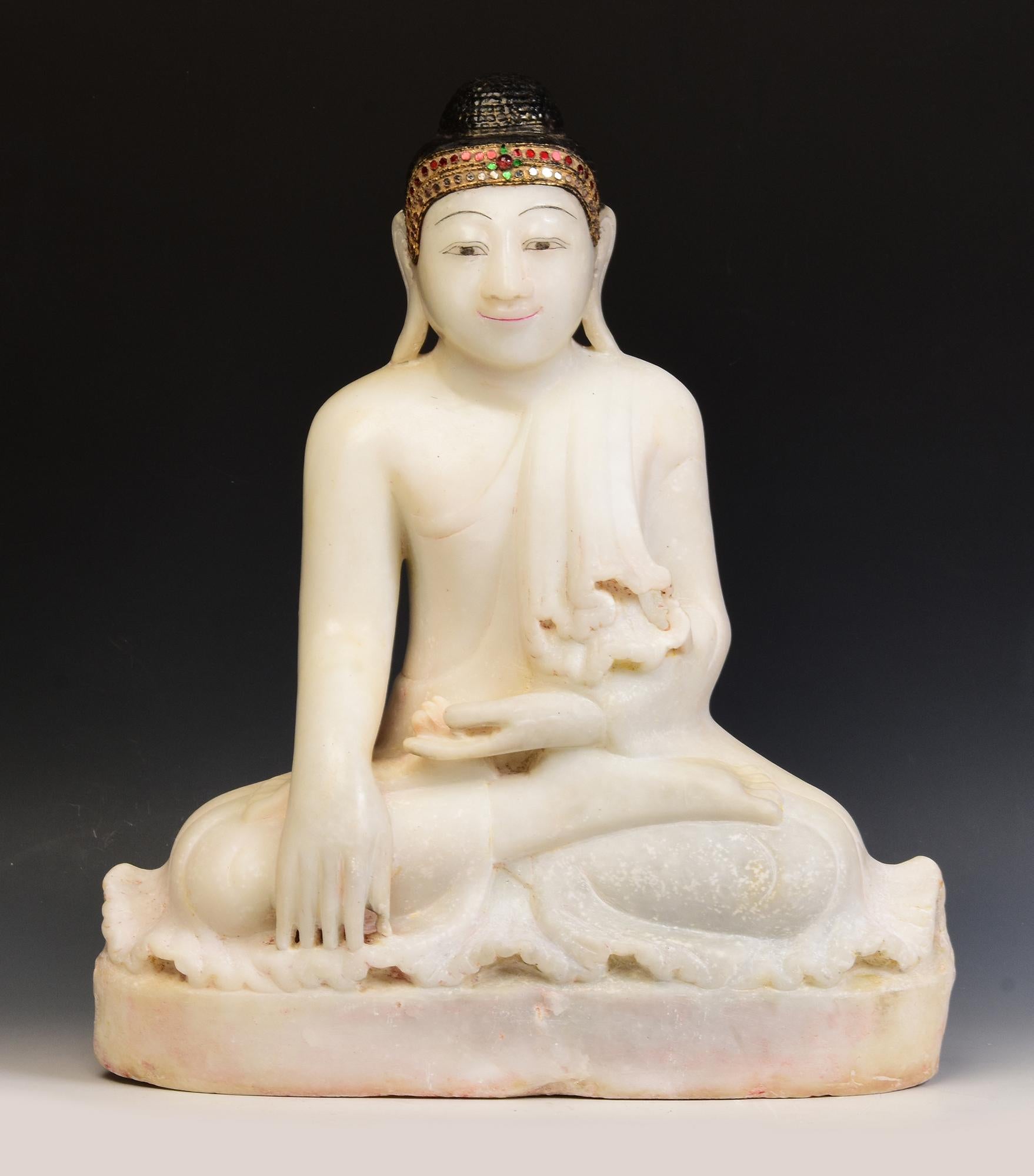 Antique Burmese alabaster Buddha sitting in Mara Vijaya (calling the earth to witness) posture on a base, with inlay of colorful glass pieces on the headband.

Age: Burma, Mandalay Period, 19th Century
Size: Height 53 C.M. / Width 54.5 C.M. / Depth