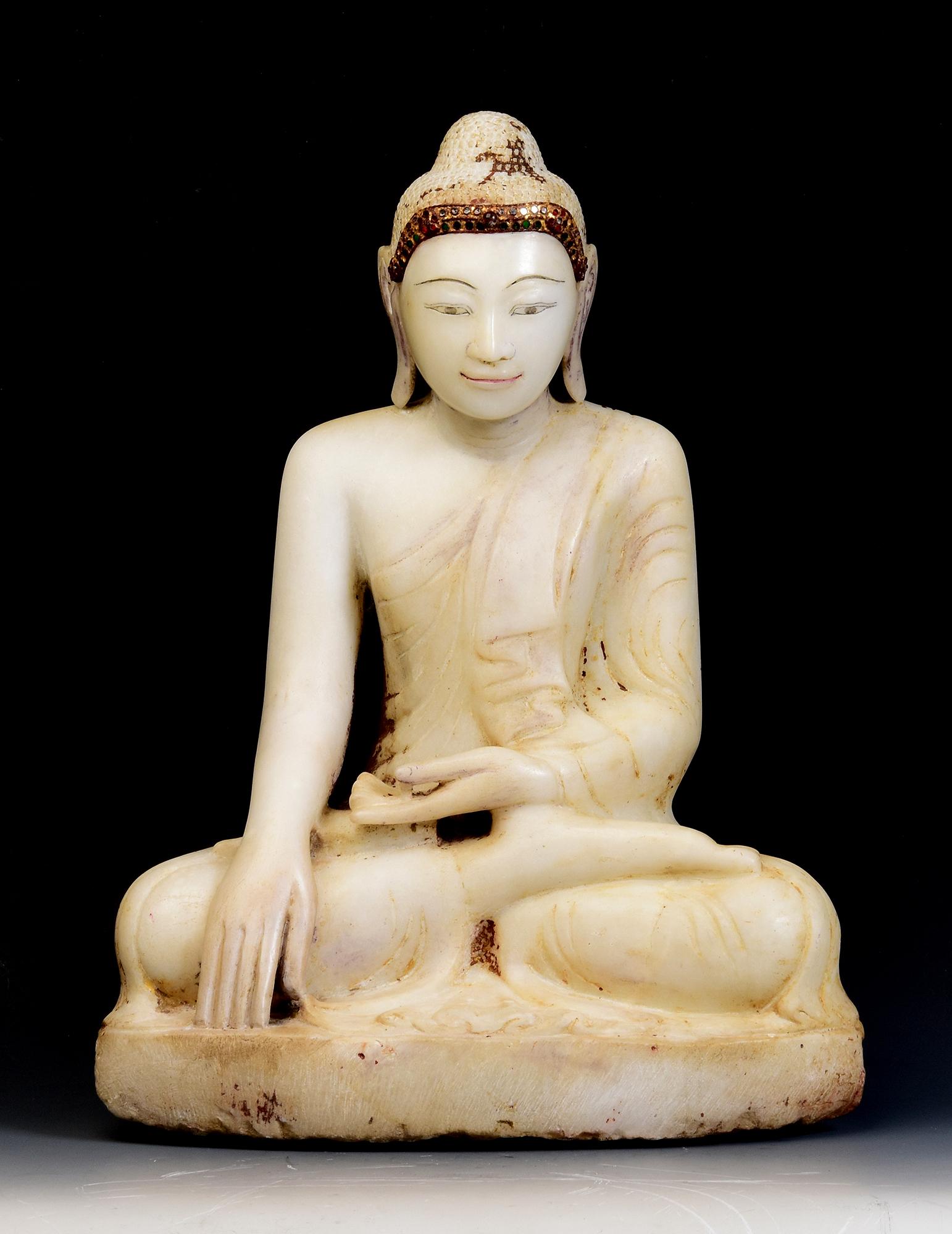 Antiker burmesischer Alabaster-Buddha in Mara-Vijaya-Haltung (die Erde zum Zeugen rufen) auf einem Sockel sitzend, mit Einlage von bunten Glasstücken auf dem Stirnband.

Alter: Birma, Mandalay-Periode, 19. Jahrhundert
Größe: Höhe 49,5 C.M. / Breite