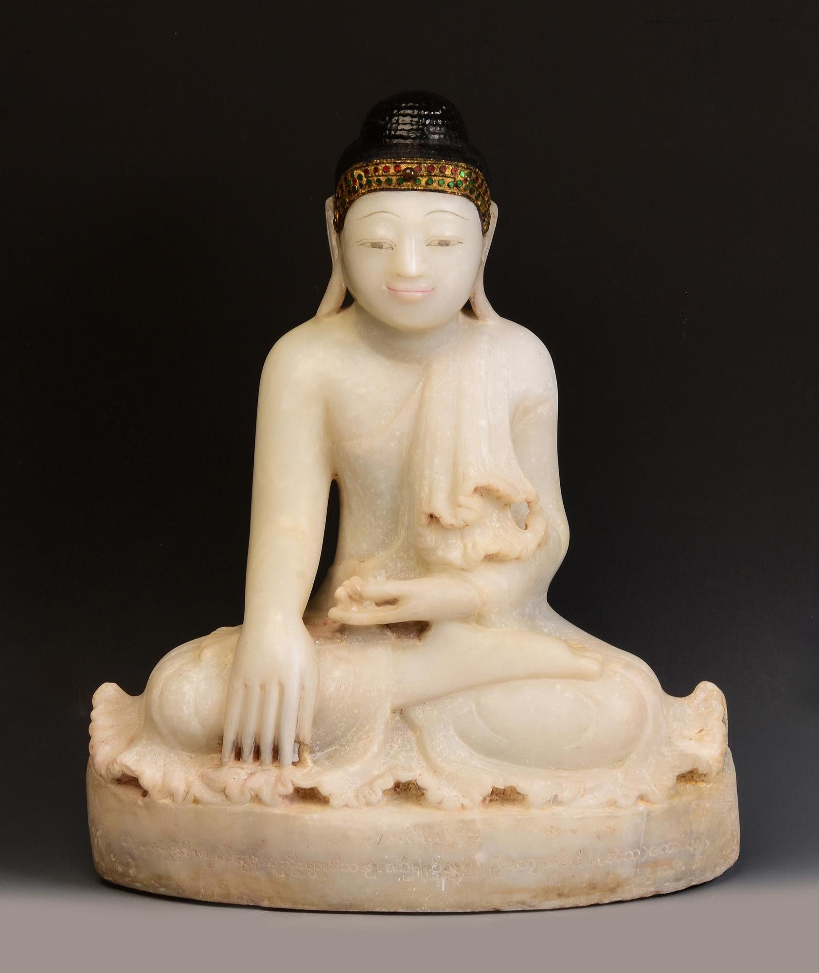 Antique Burmese alabaster Buddha sitting in Mara Vijaya (calling the earth to witness) posture on a base, with inlay of colorful glass pieces on the headband.

Age: Burma, Mandalay Period, 19th Century
Size: Height 54 C.M. / Width 44.5 C.M. / Depth