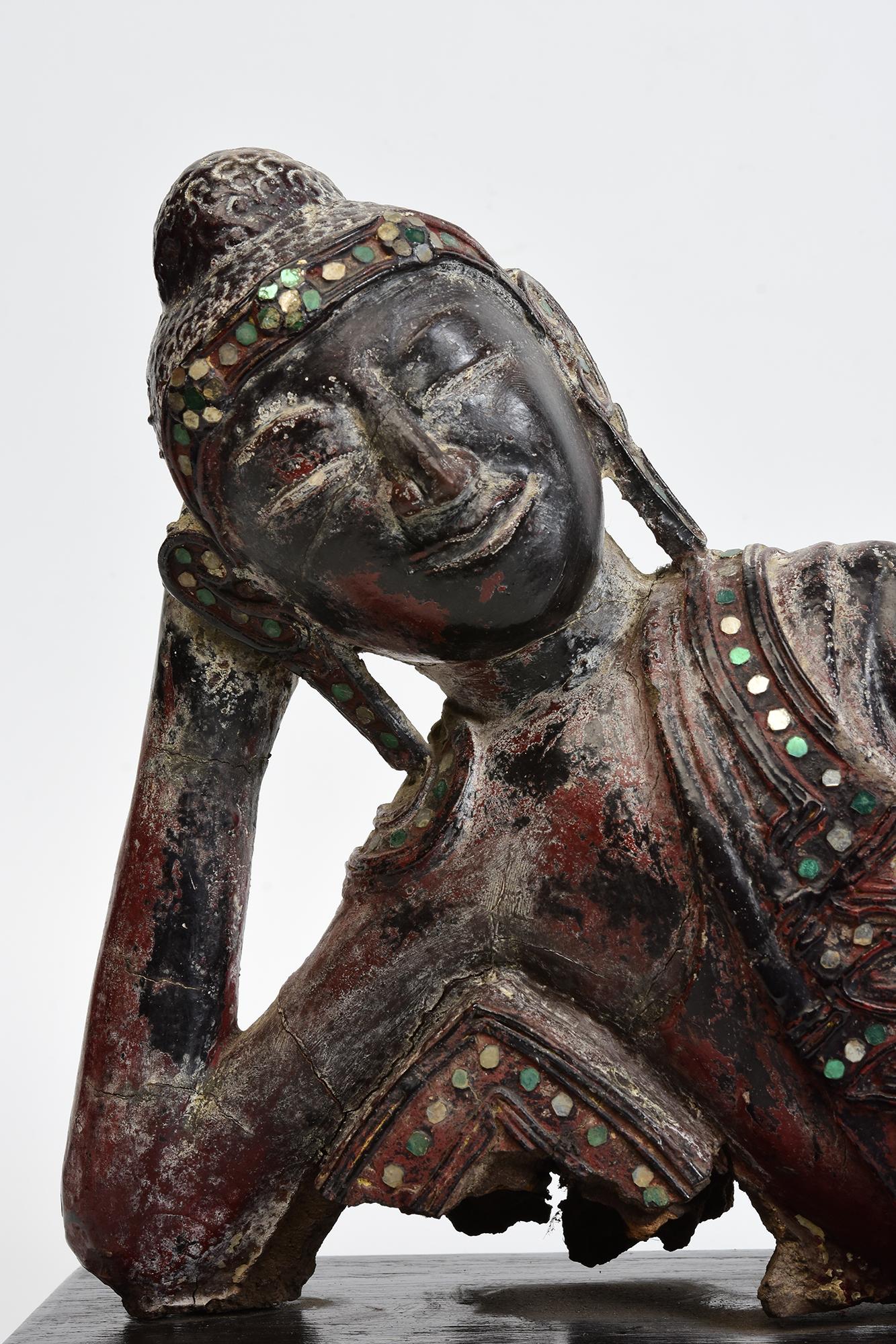 Antique Burmese wooden reclining Buddha with original lacquer and inlay of colorful glass pieces on the headband and borders of the robe..

Age: Burma, Mandalay Period, 19th Century
Size excluding stand: Length 47.6 C.M. / Width 10 C.M. / Height 22