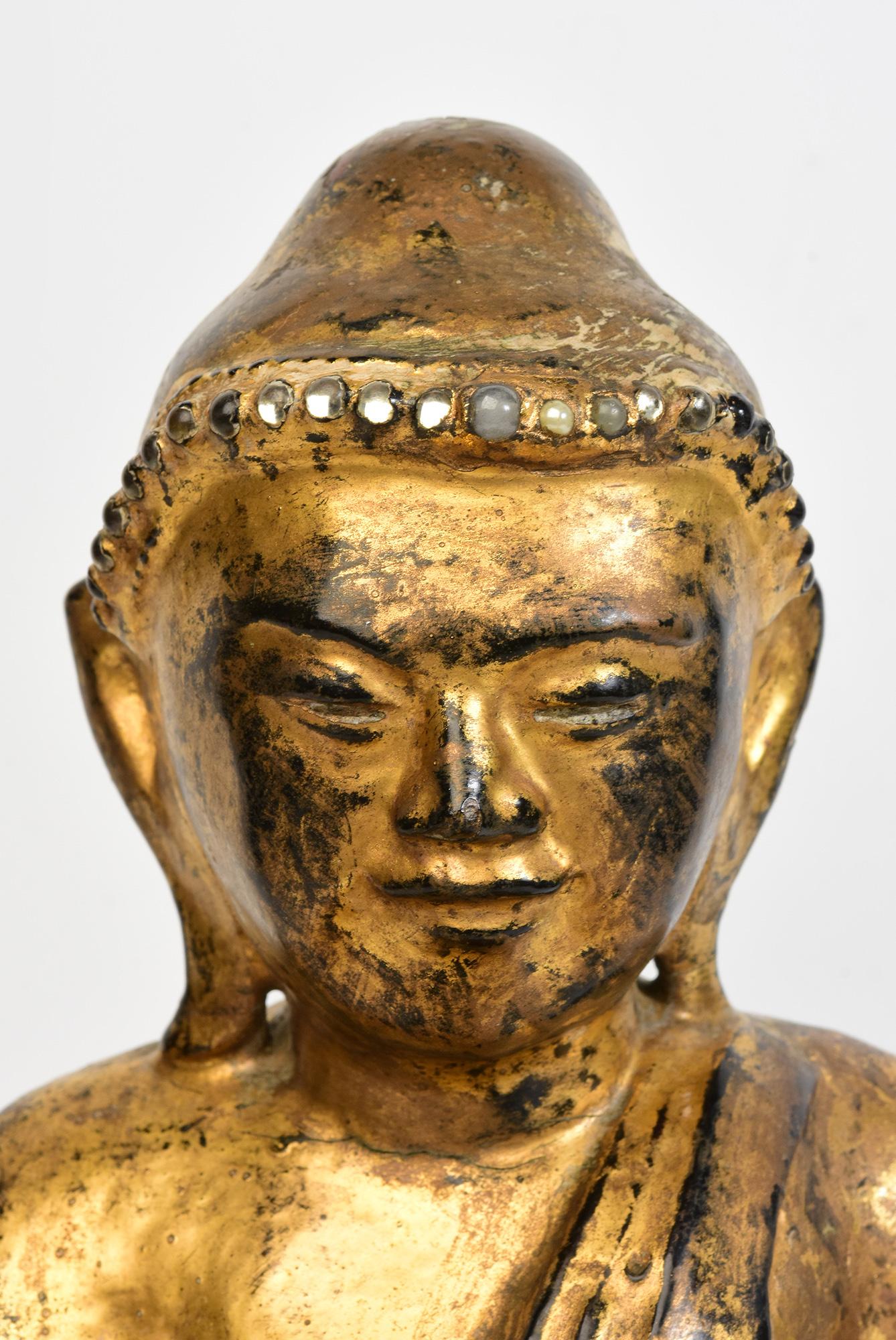 Antique Burmese wooden Buddha sitting in Mara Vijaya (calling the earth to witness) posture on a base with gilded gold and glass.

Age: Burma, Mandalay Period, 19th Century
Size: Height 39.7 C.M. / Width 32 C.M. / Depth 25 C.M.
Condition: Nice