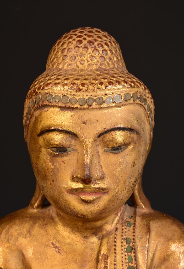 Buddha aus birmanischem Holz auf einem Lotussockel stehend, mit vergoldetem Gold und Einlagen aus bunten Glasstücken am Stirnband und an den Rändern des Gewandes.

Alter: Birma, Mandalay-Periode, 19. Jahrhundert
Größe: Höhe 54,5 C.M. / Breite 29,9
