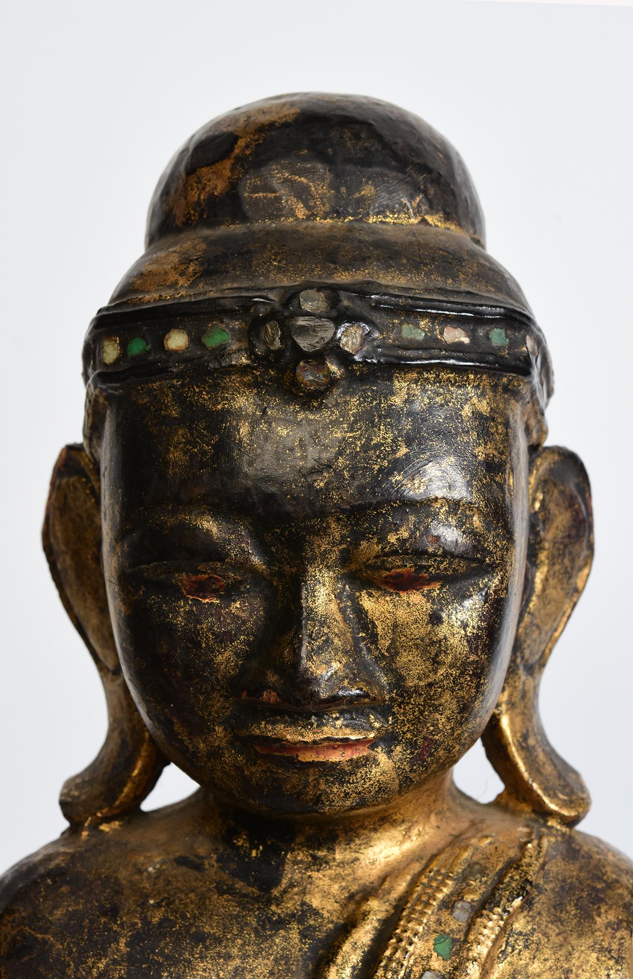 Antiker burmesischer Holzbuddha auf einem Lotussockel stehend, mit Lackierung, Vergoldung und Einlage von bunten Glasstücken am Stirnband und an den Rändern des Gewandes. 

Alter: Birma, Mandalay-Periode, 19. Jahrhundert
Größe des Buddhas allein: