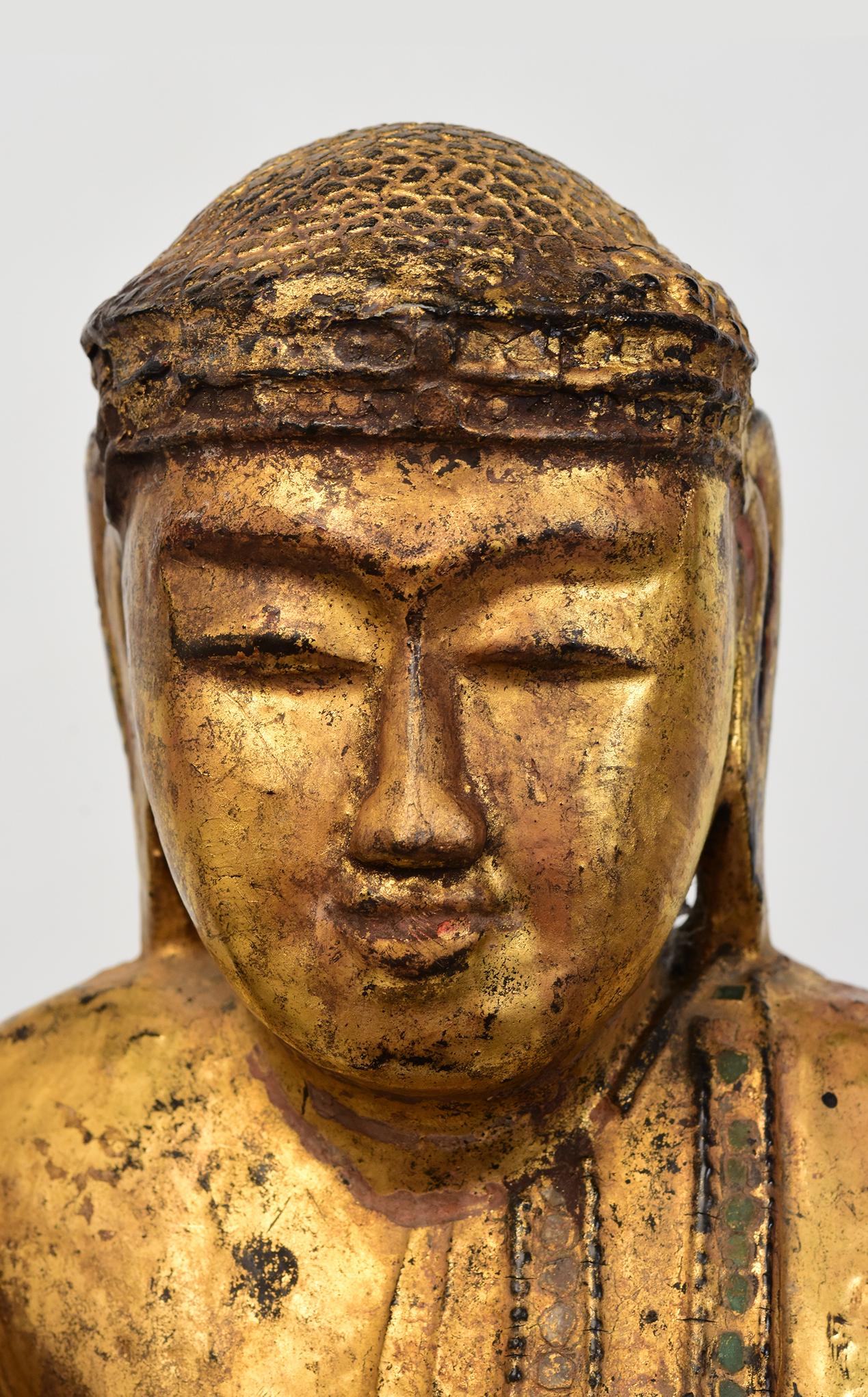 Antiker burmesischer Holzbuddha auf einem Lotussockel stehend, mit vergoldetem Gold und Einlage von bunten Glasstücken an den Rändern des Gewandes.

Alter: Birma, Mandalay-Periode, 19. Jahrhundert
Größe ohne schwarzen Ständer: Höhe 54 C.M. / Breite