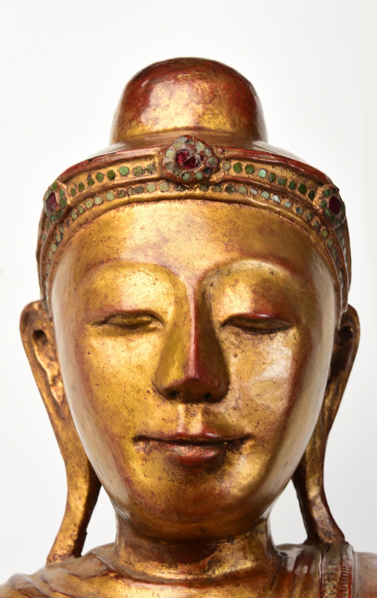Antique Burmese wooden Buddha standing on a lotus base, with gilded gold and inlay of colorful glass pieces on the headband and borders of the robe.

Age: Burma, Mandalay Period, 19th Century
Size excluding black stand: Height 99.2 C.M. / Width 44.2