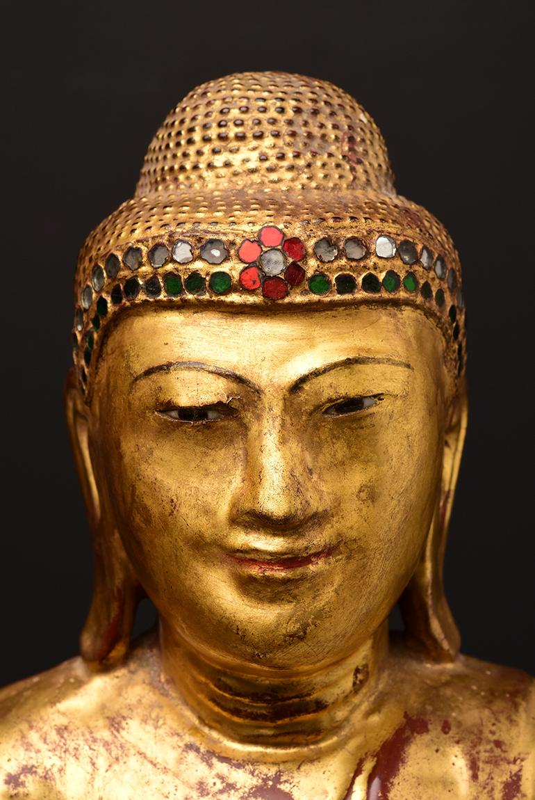 Burmese wooden Buddha standing on a lotus base, with gilded gold and inlay of colorful glass pieces on the headband.

Age: Burma, Mandalay Period, 19th Century
Size: Height 53.5 C.M. / Width 27.3 C.M.
Size including stand: Height 72.4