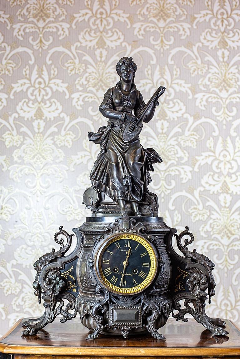 W present you this big, figurative mantel clock from the second half of the 19th century.
It is made of bronze, with black marble insets.
The clock strikes halves and full hours.

The mechanism is functional, after a horological