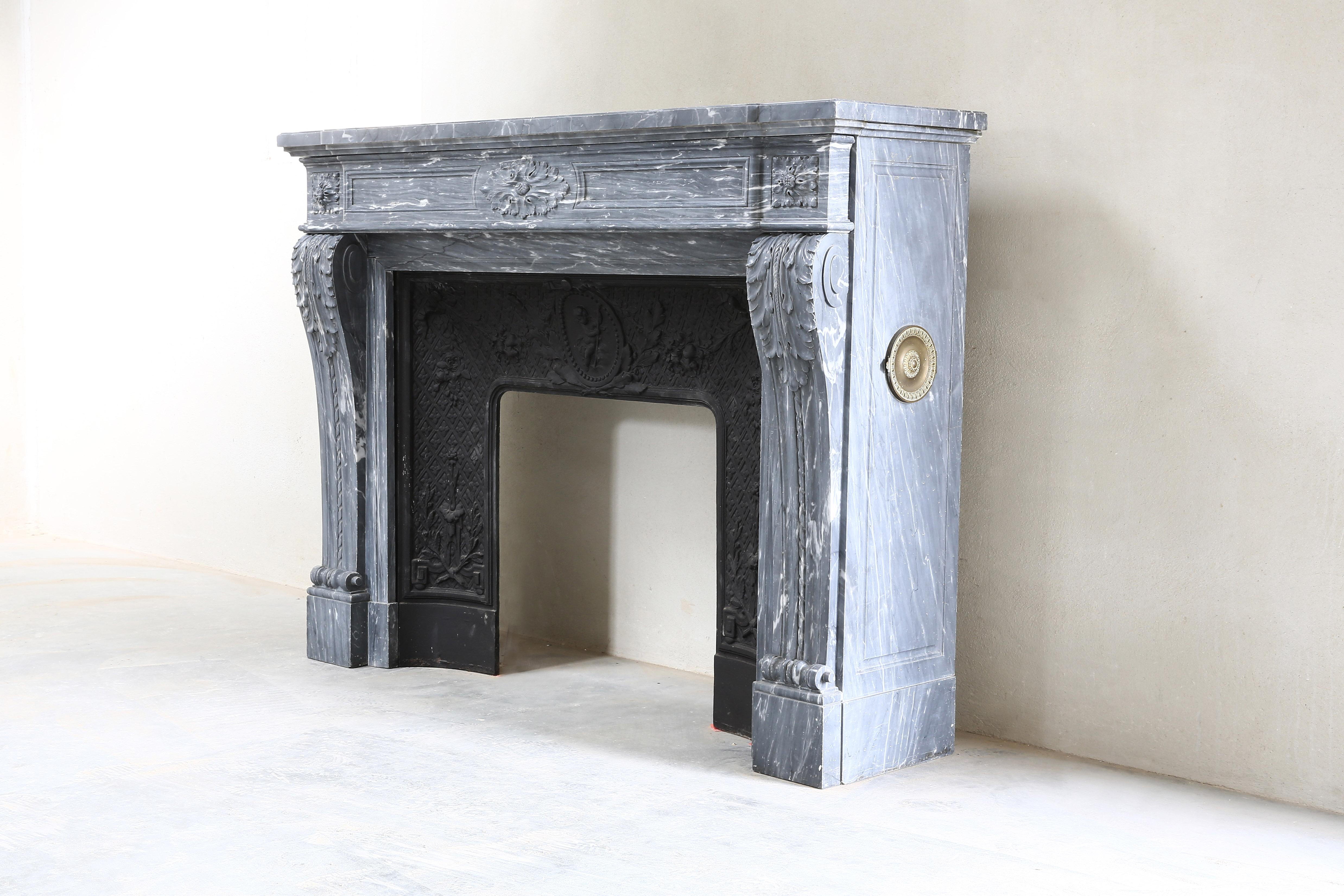 Beautiful antique fireplace of blue Turquin marble in the style of Louis XVI from the 19th century. This fireplace still has the original cast iron insert, a beautiful part of this fireplace. The front part has various elements and acanthus leaves